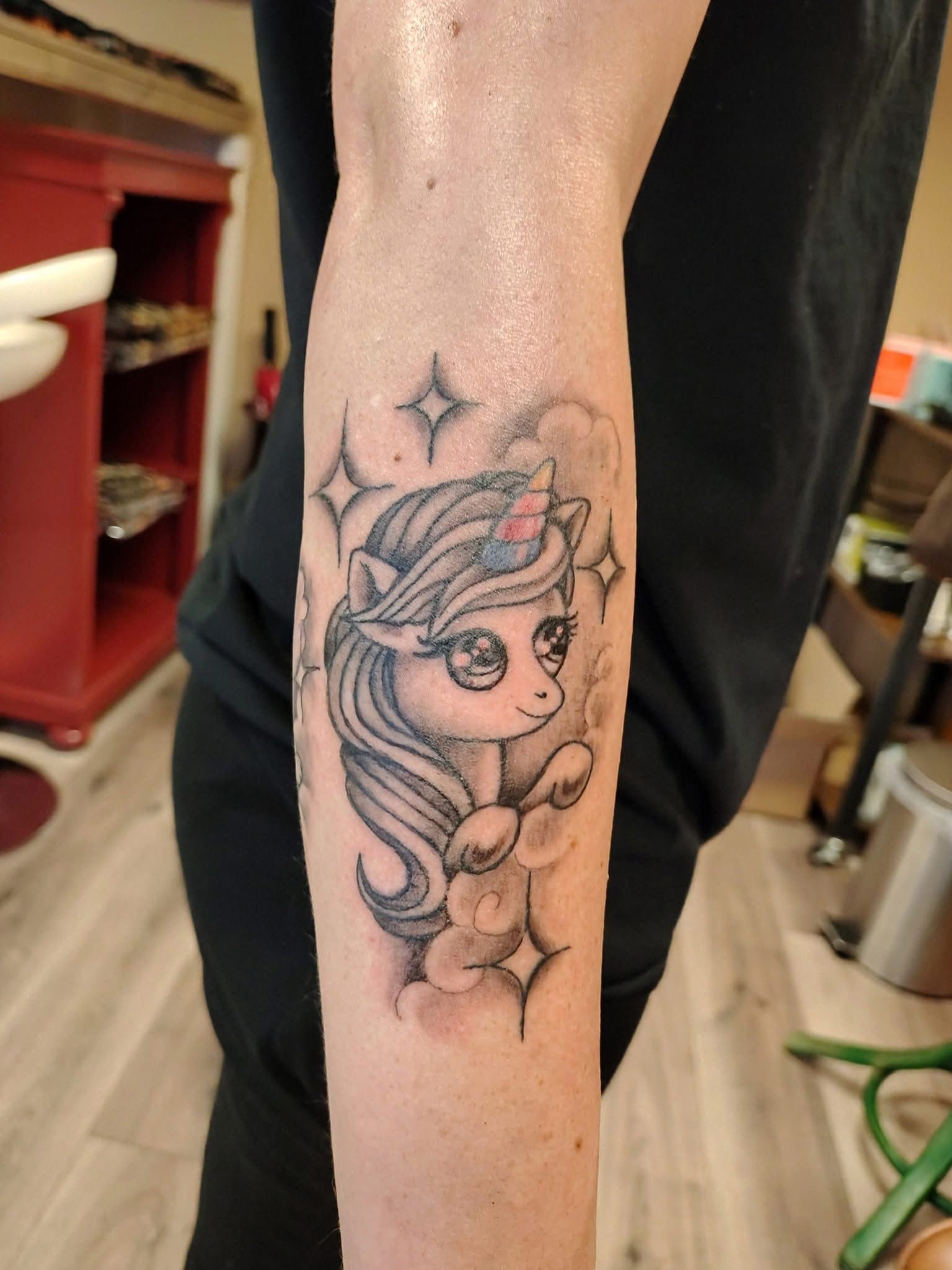 Close-up van een onderarmtattoo van een schattige tekenfilmprinses met sterren op de vloer van een kapsalon.