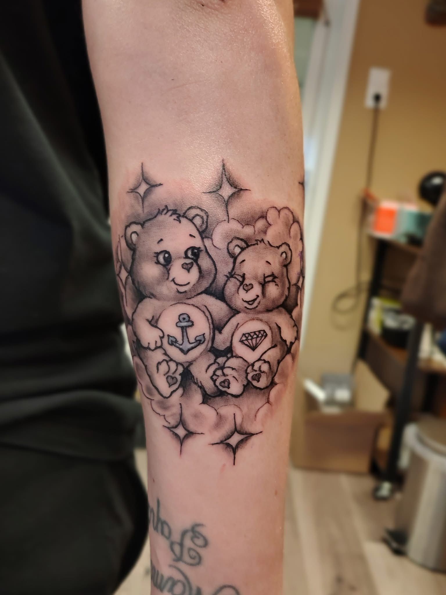 Close-up van een onderarmtattoo met twee teddyberen met glitter, gecentreerd op de arm.