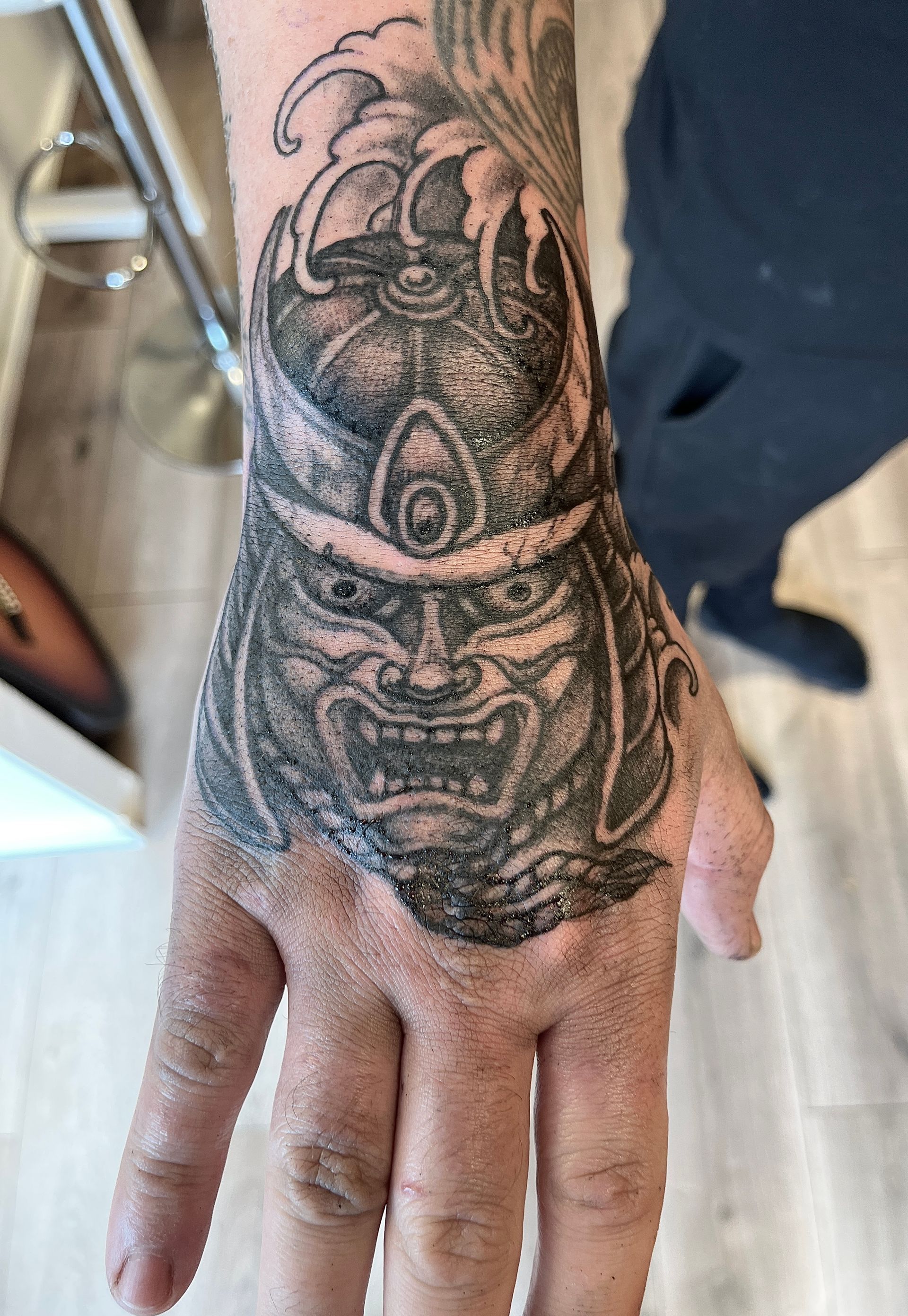 Close-up van een hand met een zwarte tatoeage op de rug en vingers.
