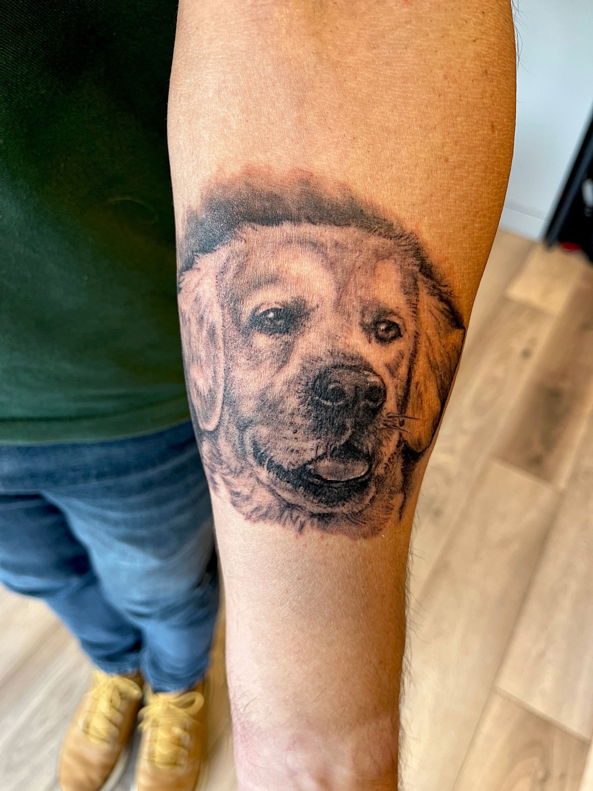 Arm met een realistische tatoeage van een hondengezicht op de onderarm