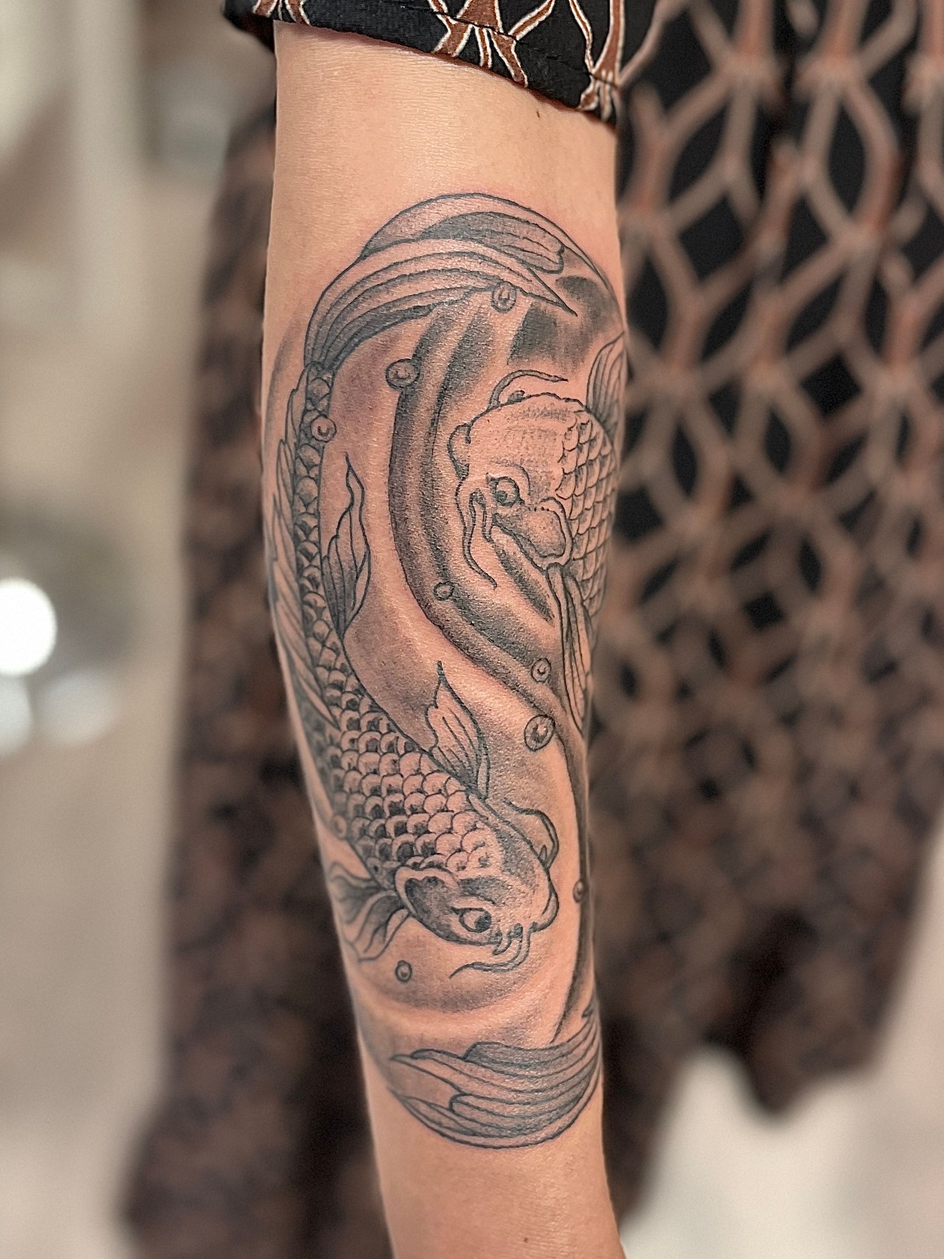 Zwart-grijze slangentattoo op een onderarm, van dichtbij weergegeven.