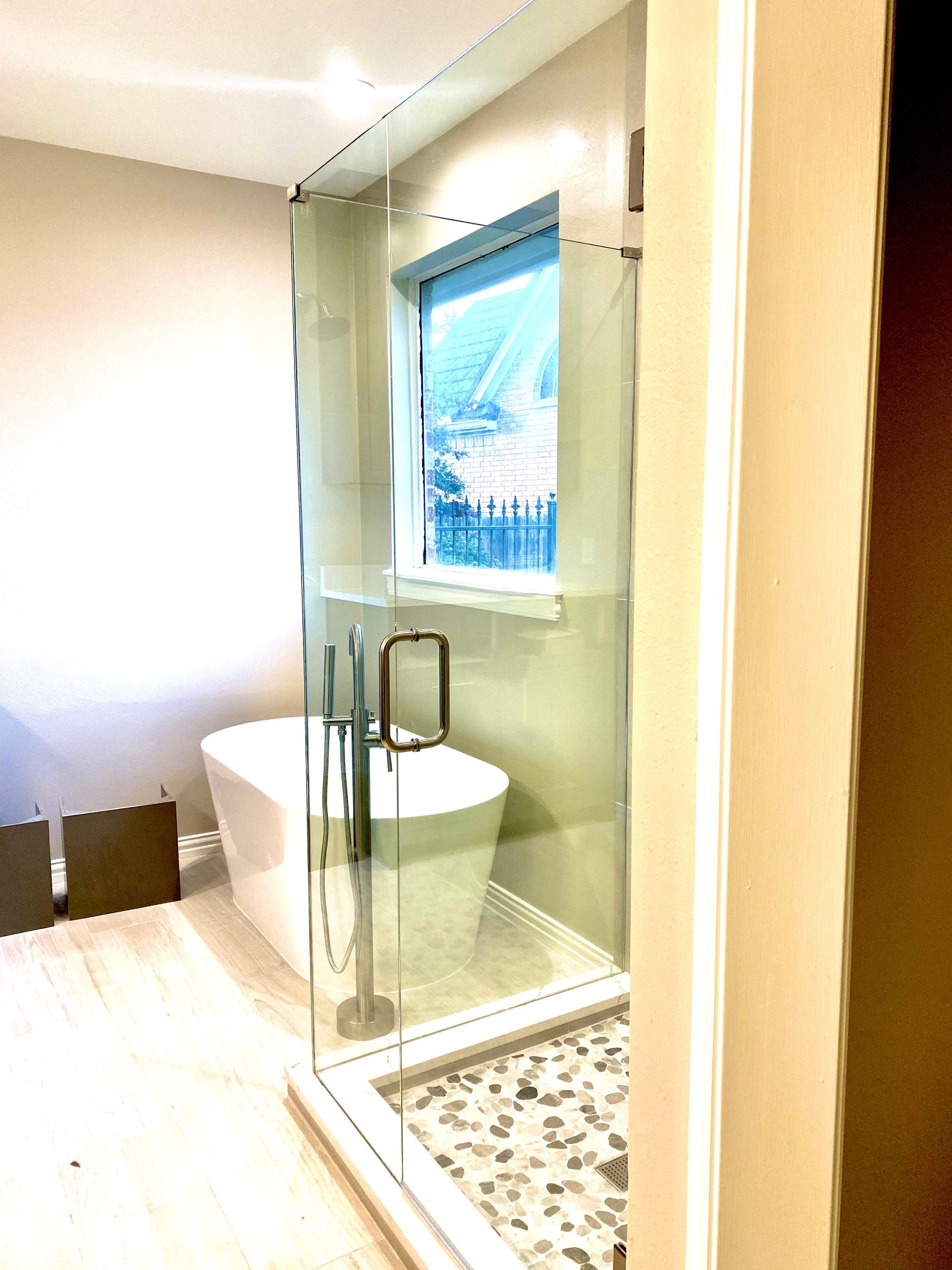 Modern bathroom with glass shower enclosure, white toilet, and window with blue blinds.