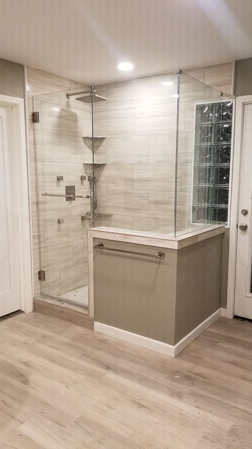 Modern bathroom with glass shower, beige tile, and a large corner tub surround