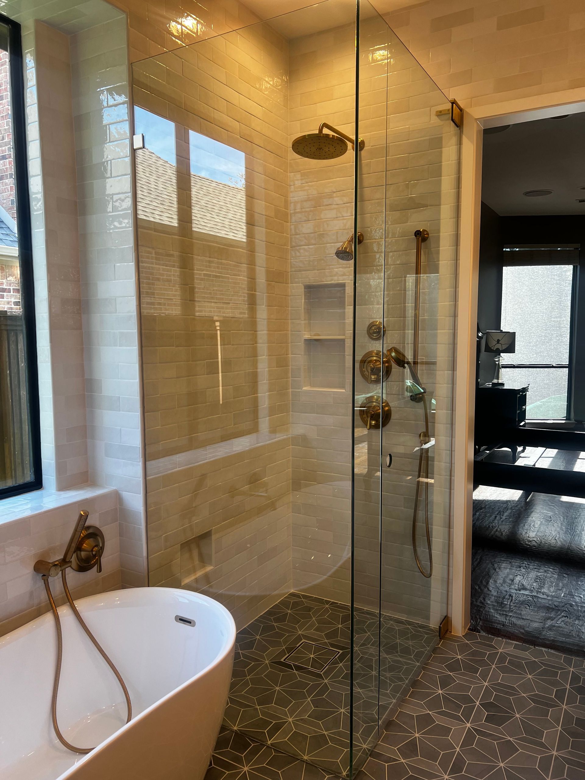 Modern bathroom with glass shower, freestanding tub, and pebble tile floor.