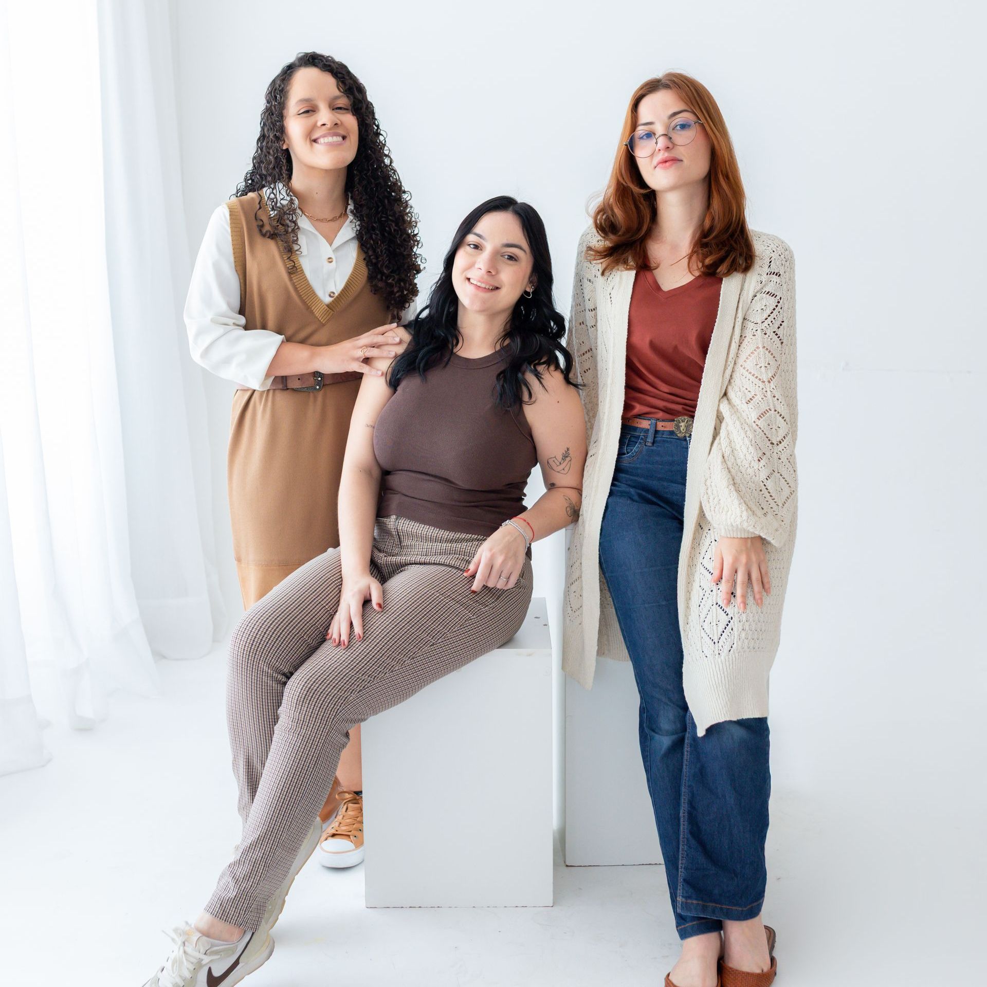 Três mulheres estão de pé, uma ao lado da outra, em uma sala.