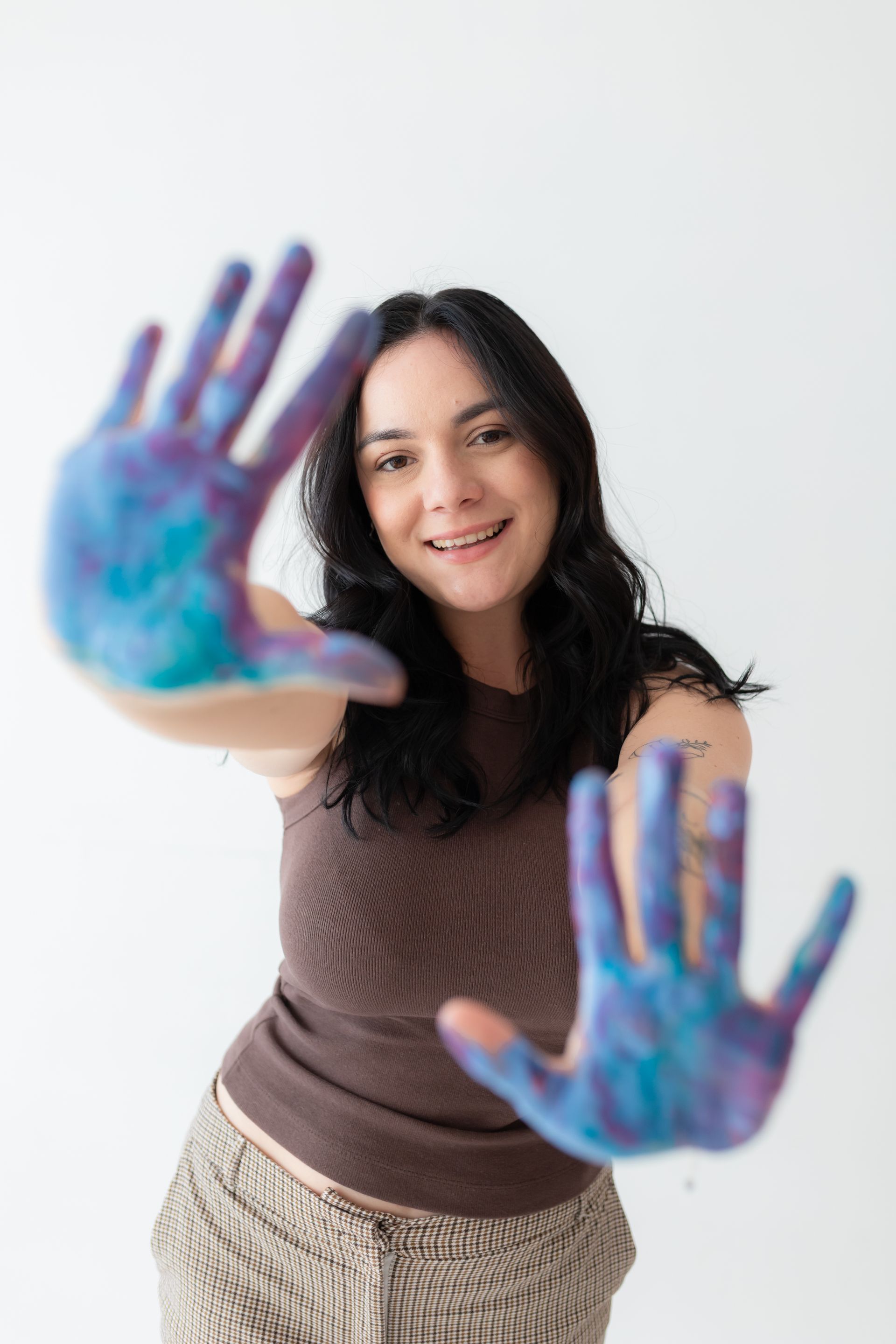Uma mulher está segurando as mãos pintadas em cores diferentes.