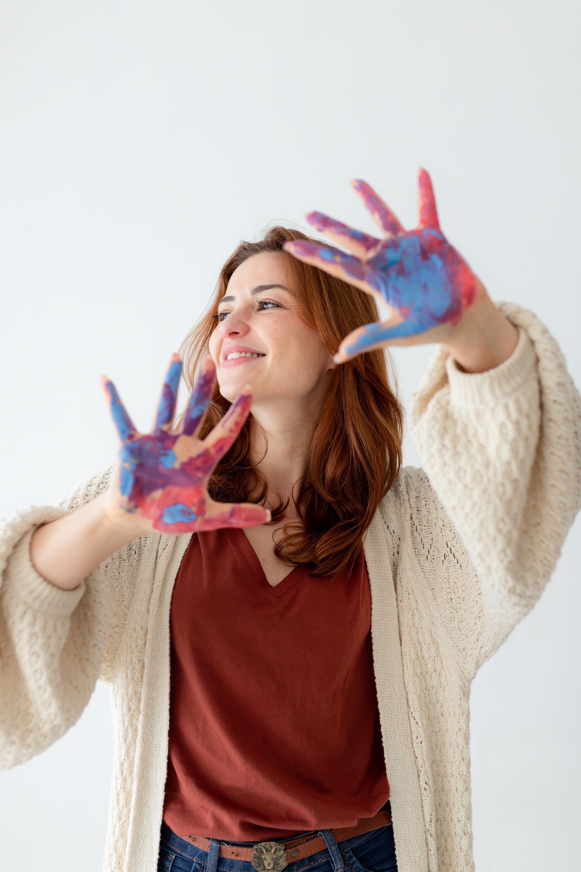 Uma mulher está segurando as mãos pintadas em cores diferentes.