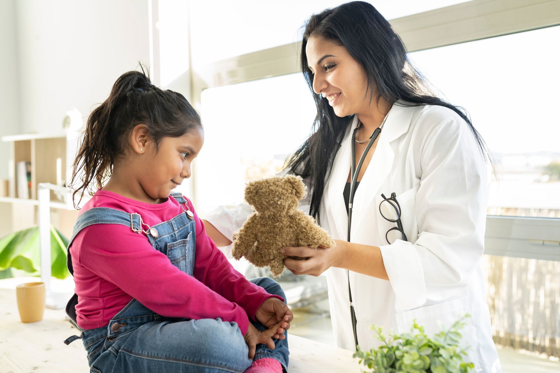 female doctor gives teddy bear to children. female doctor gives teddy bear to children.