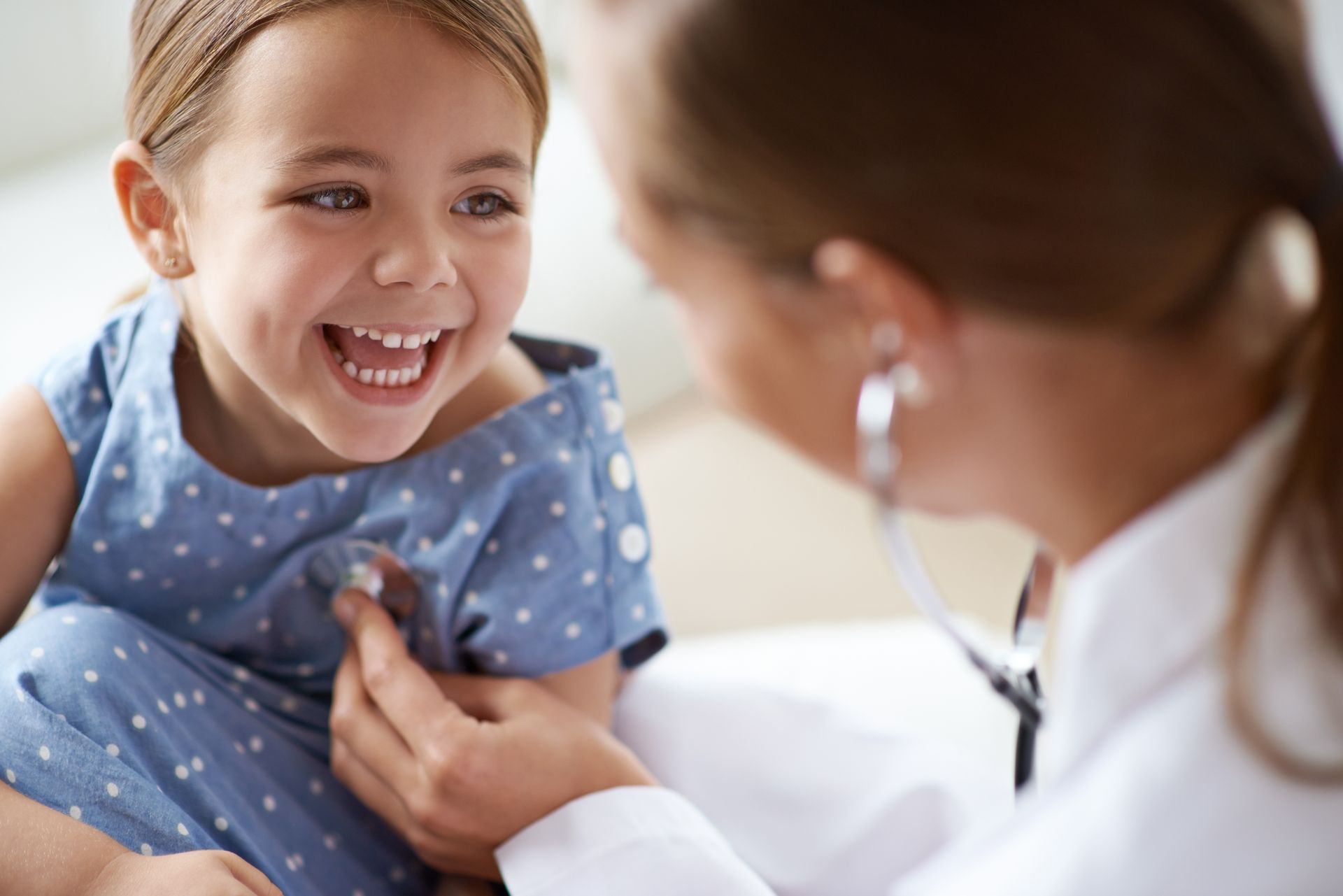 A pediatrician performing a chest assessment on a little girl with a stethoscope for pediatric care.