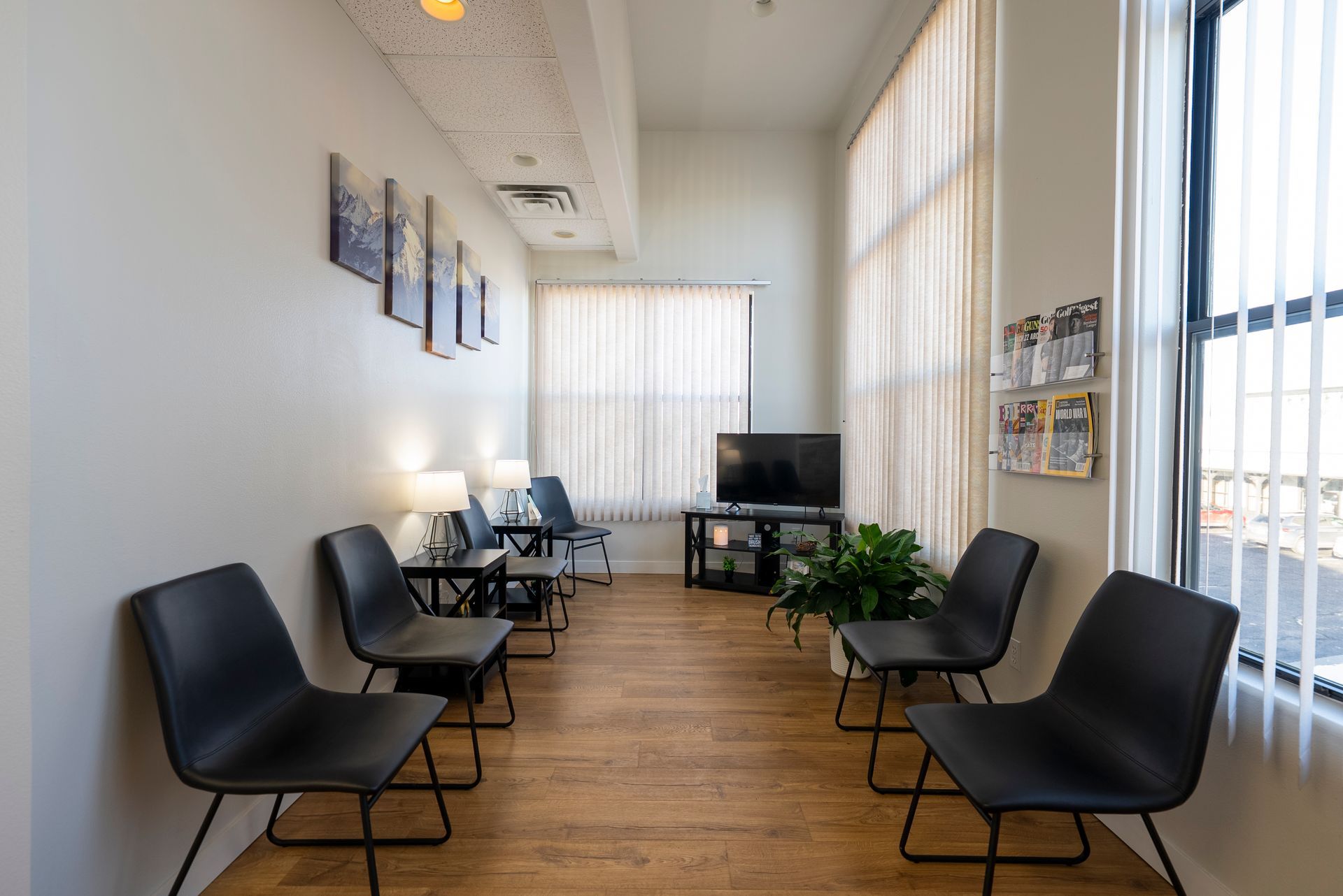 Waiting room with teal chairs, window with blinds, carpet, and lamps.