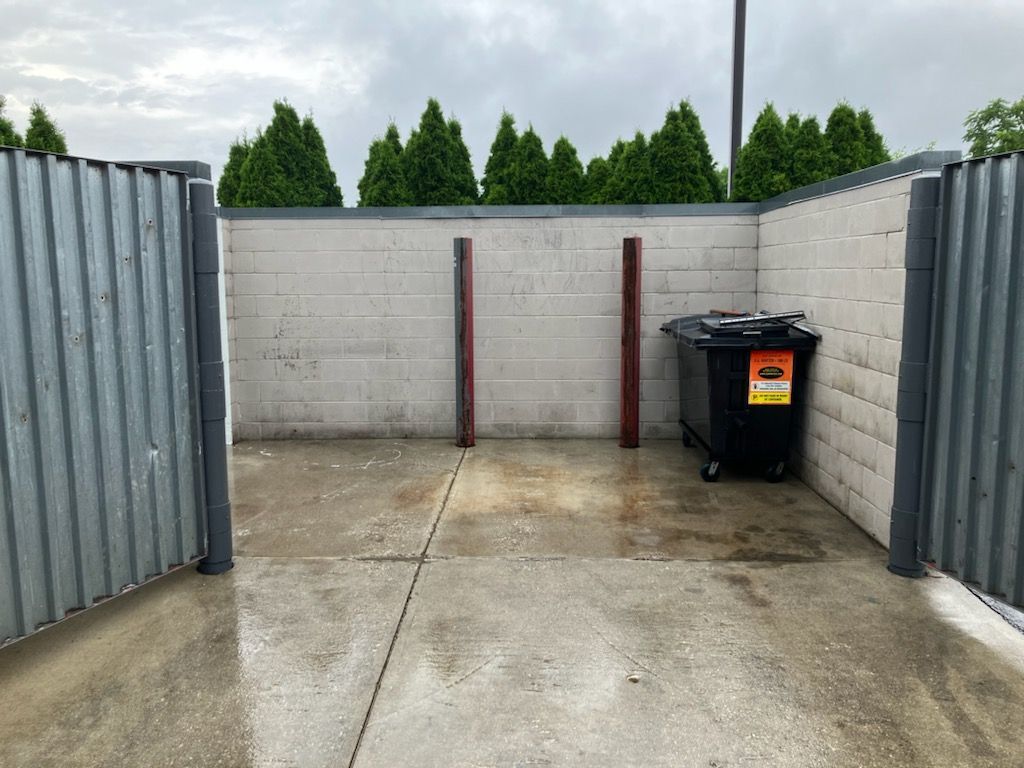 There is a trash can in the middle of the parking lot.