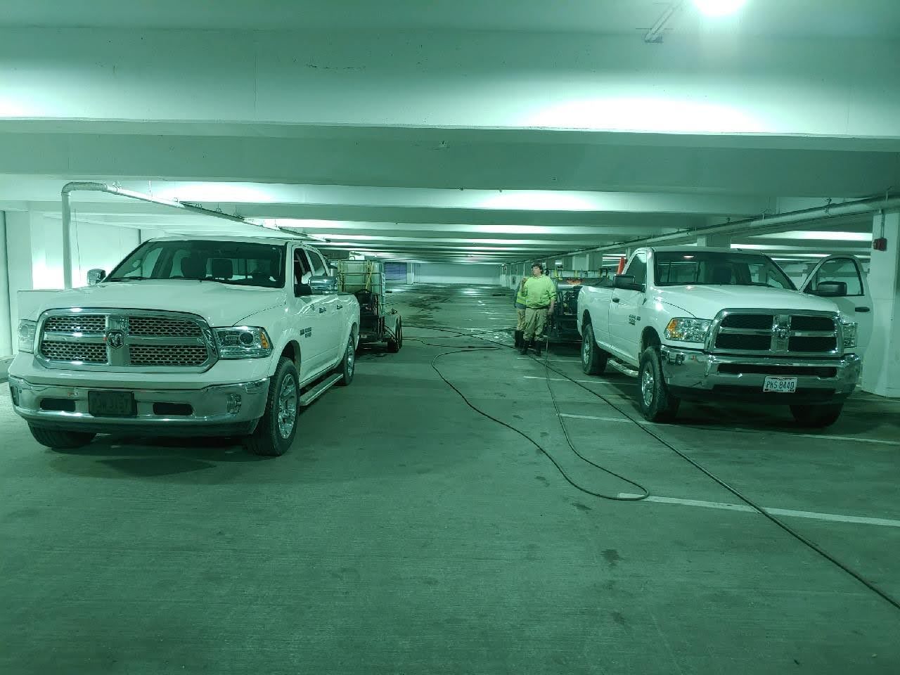 Two white trucks are parked in a parking garage.