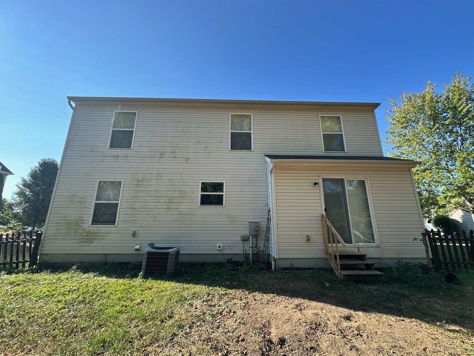 The back of a house with a lot of windows and a fence.