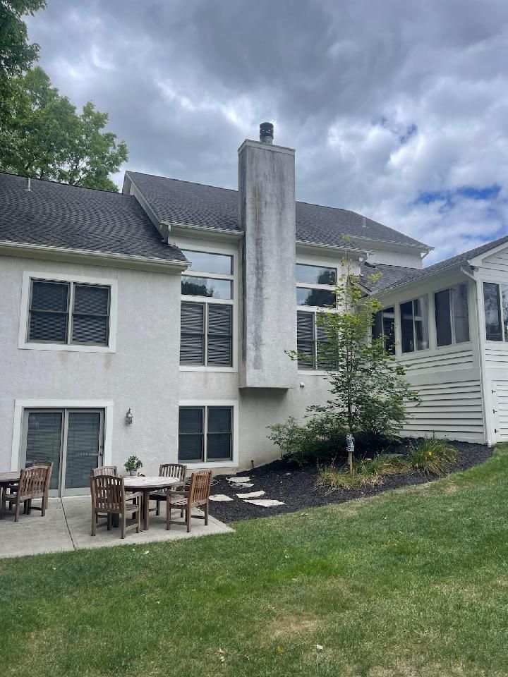 The back of a house with a patio area and a chimney.