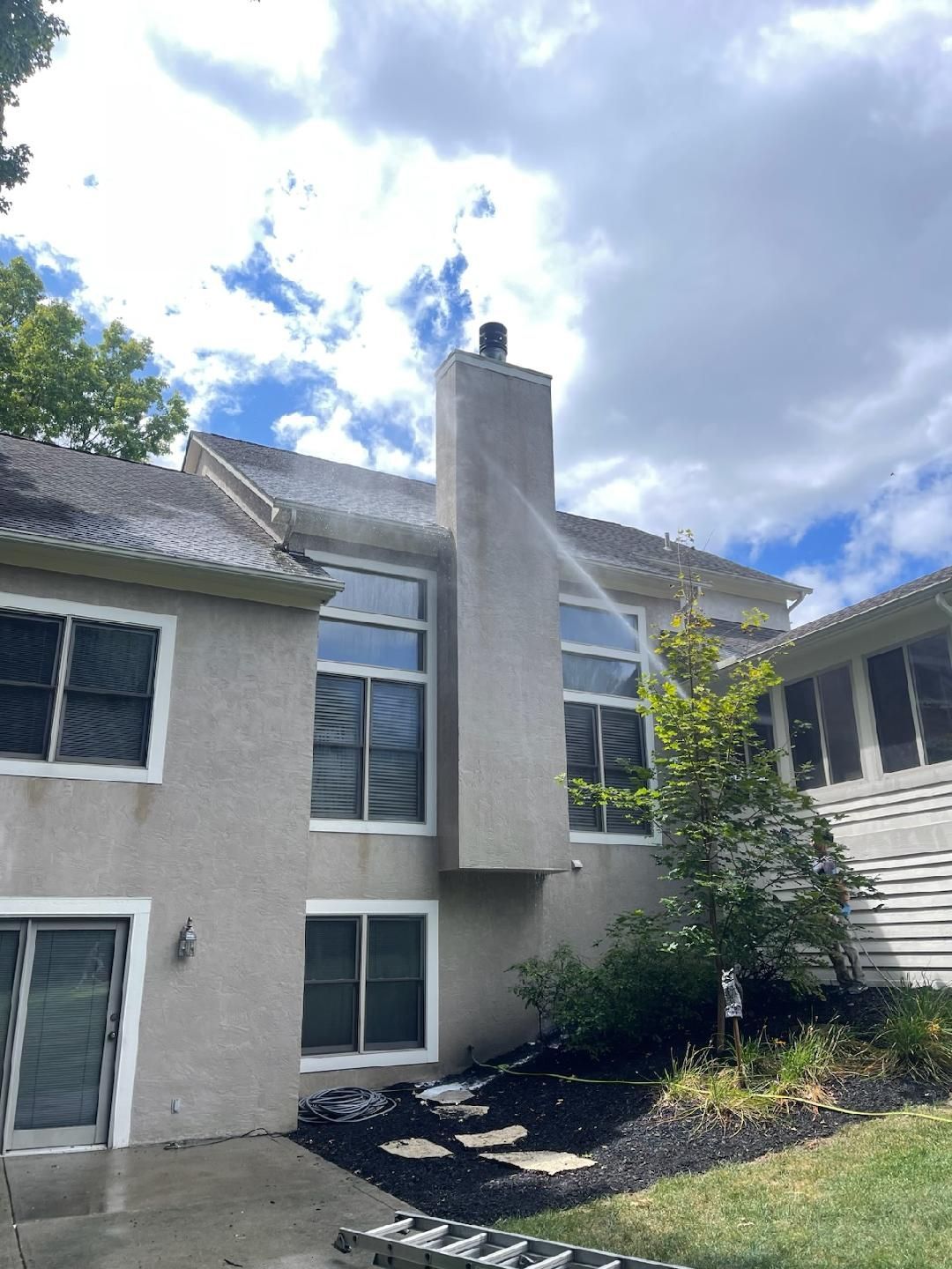 A house is being cleaned with a high pressure washer.