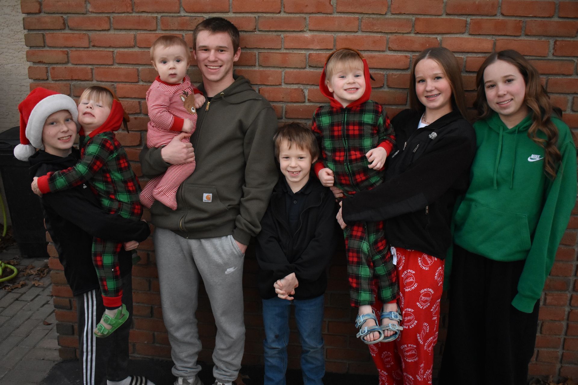 A family is posing for a picture in front of a brick wall.