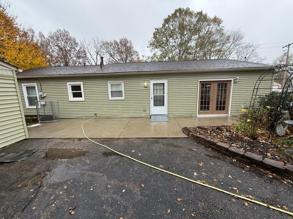 A house with a concrete patio and a hose in front of it after clean.
