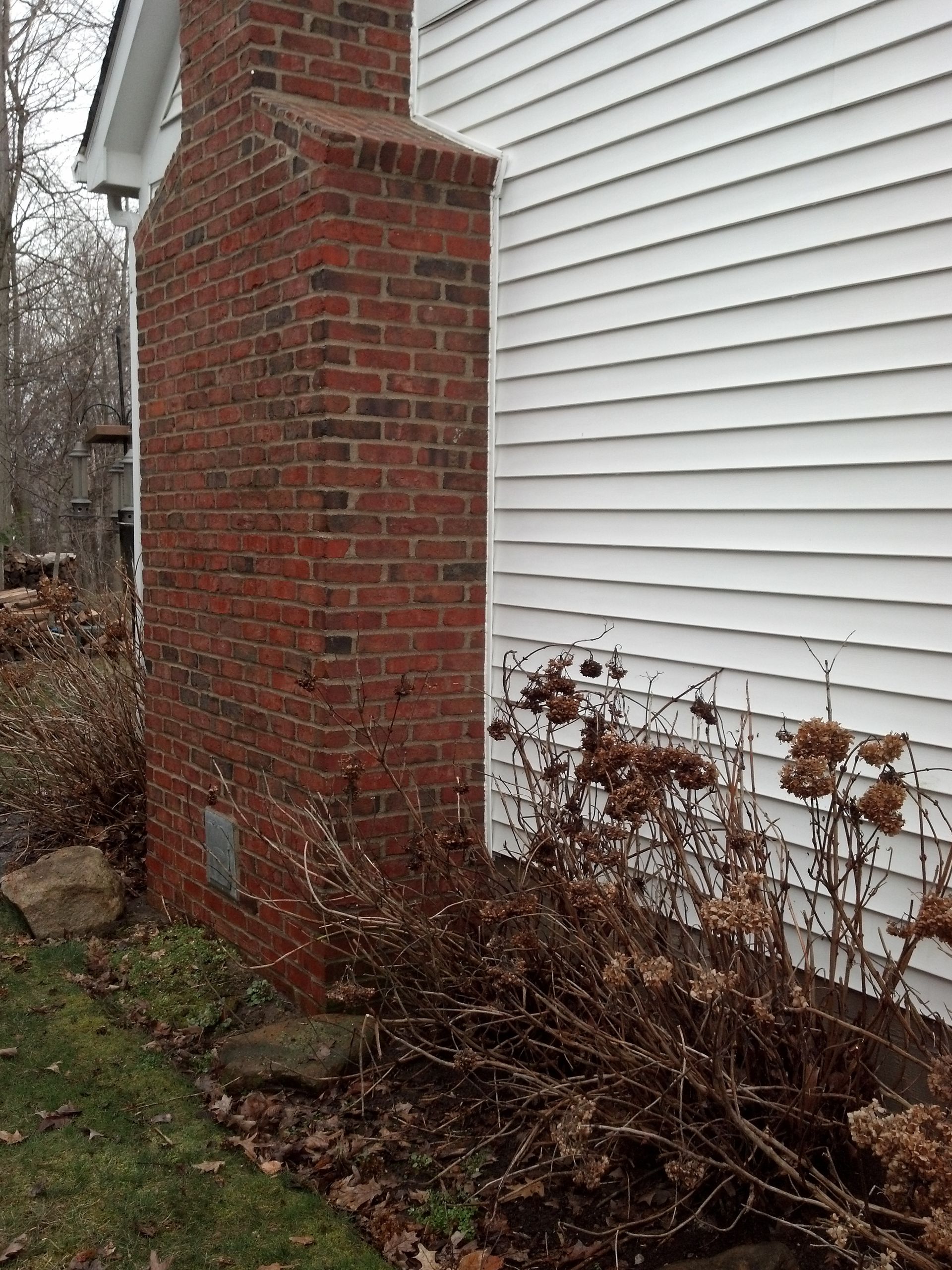 There is a brick chimney on the side of a house.
