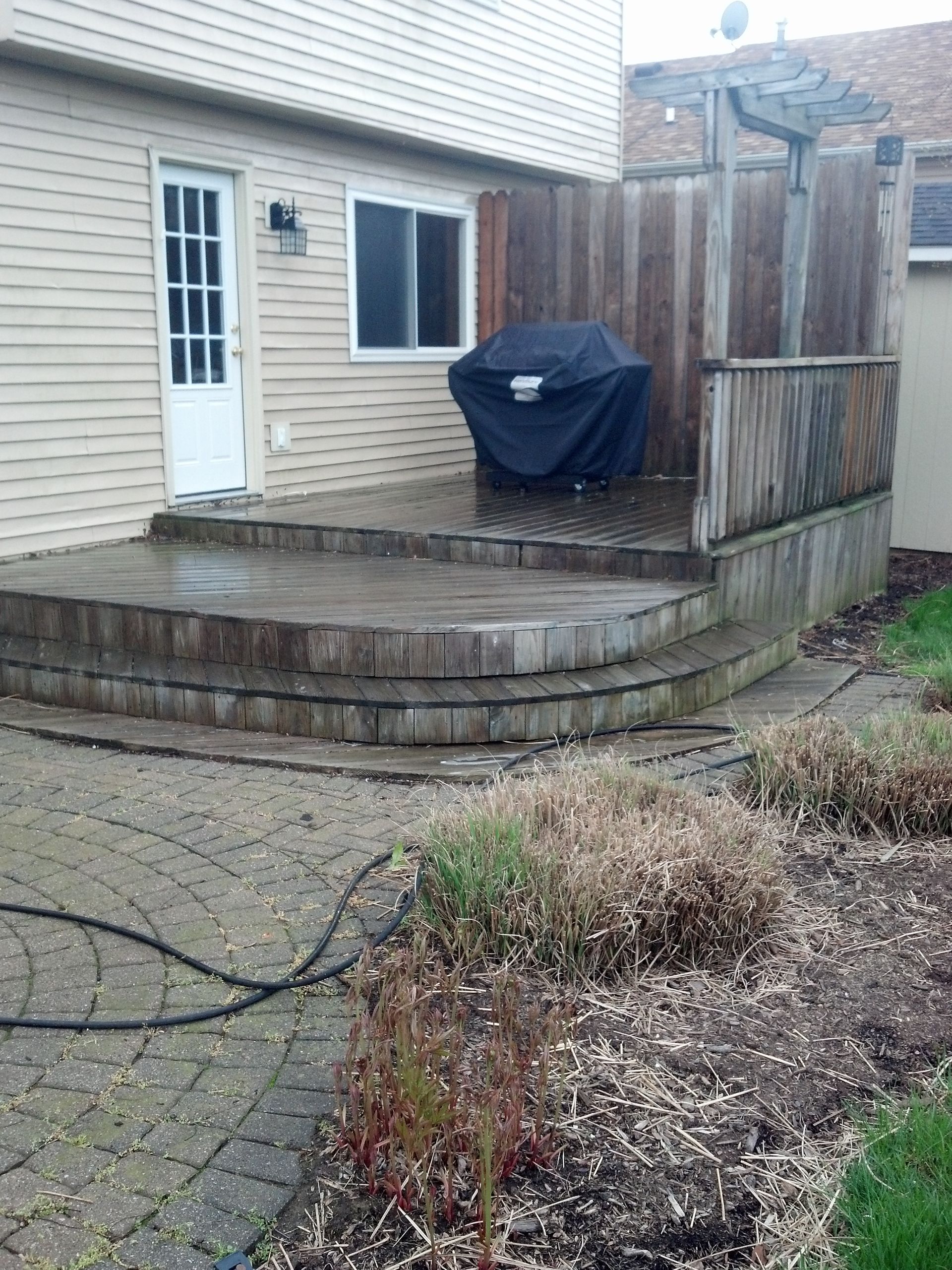 A patio with steps and a grill in the backyard of a house.
