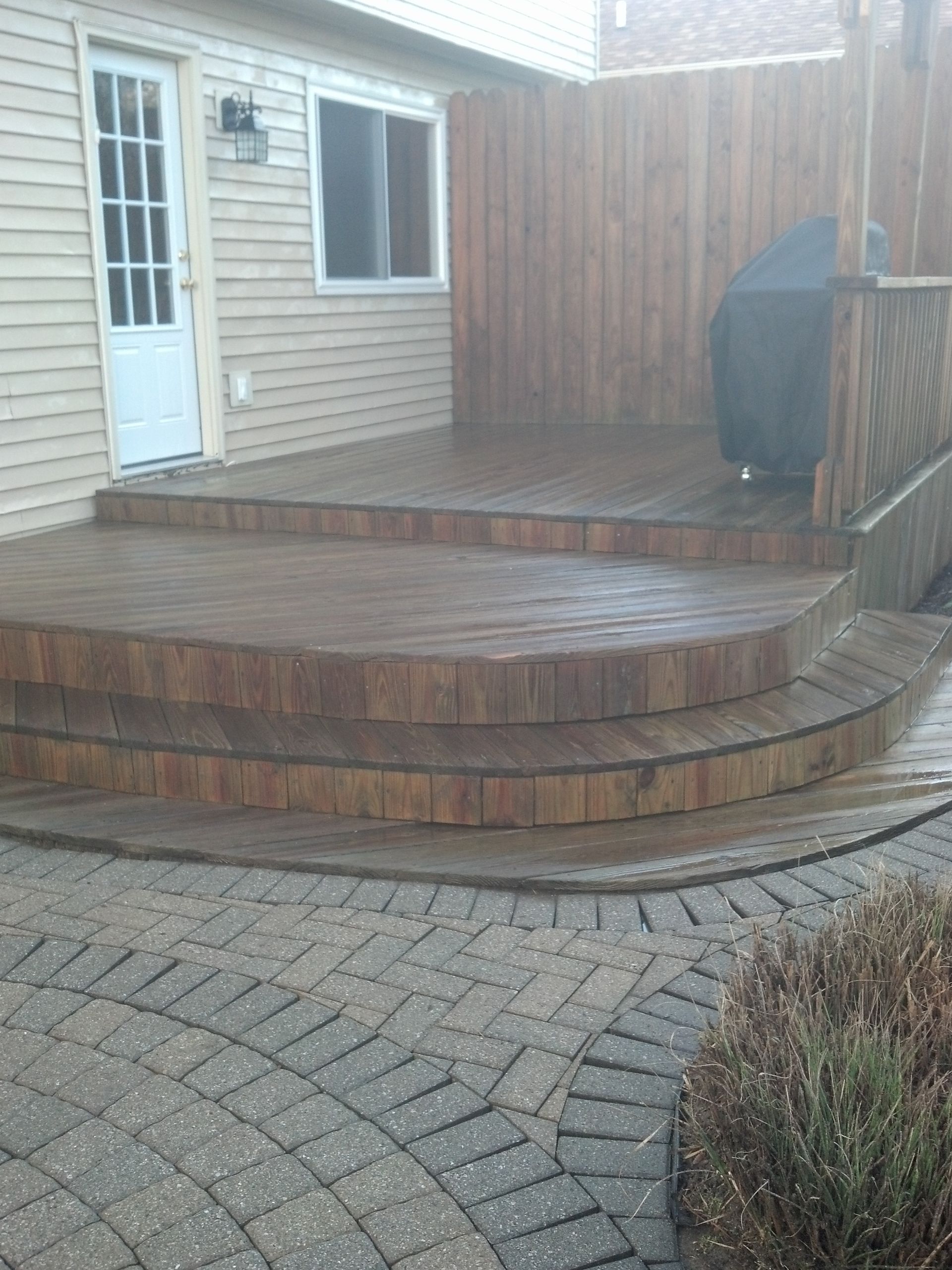 A wooden deck with stairs leading up to it in front of a house.