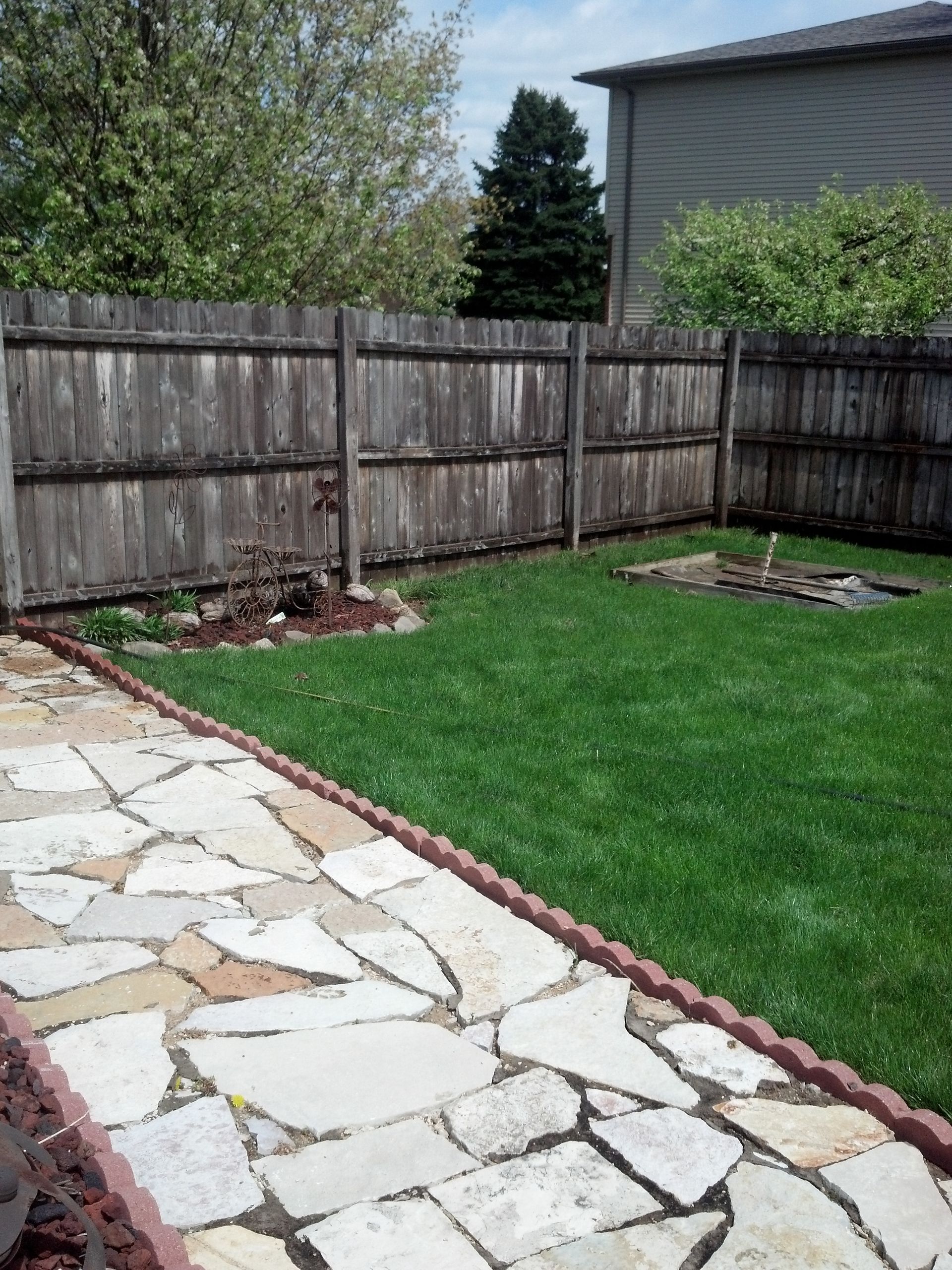A backyard with a wooden fence and a stone walkway