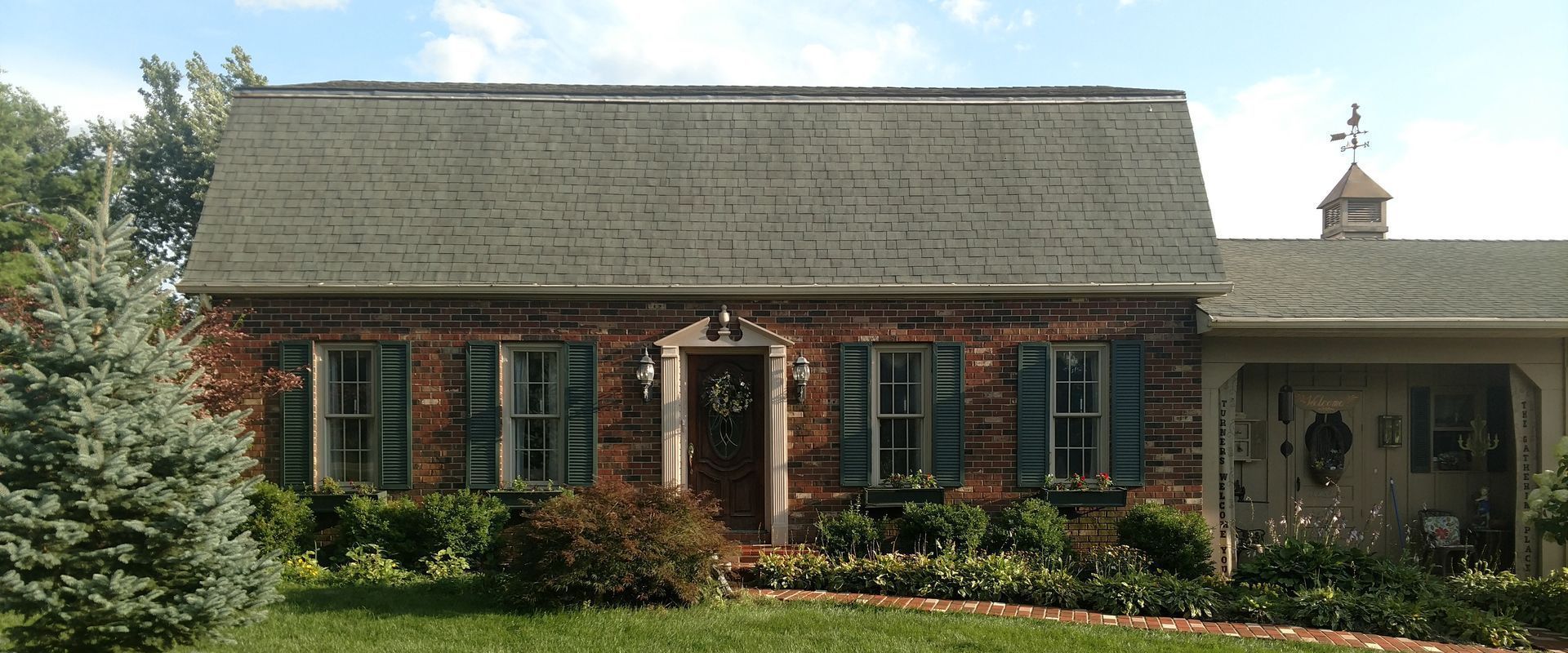 A brick house with blue shutters on the windows after clean.