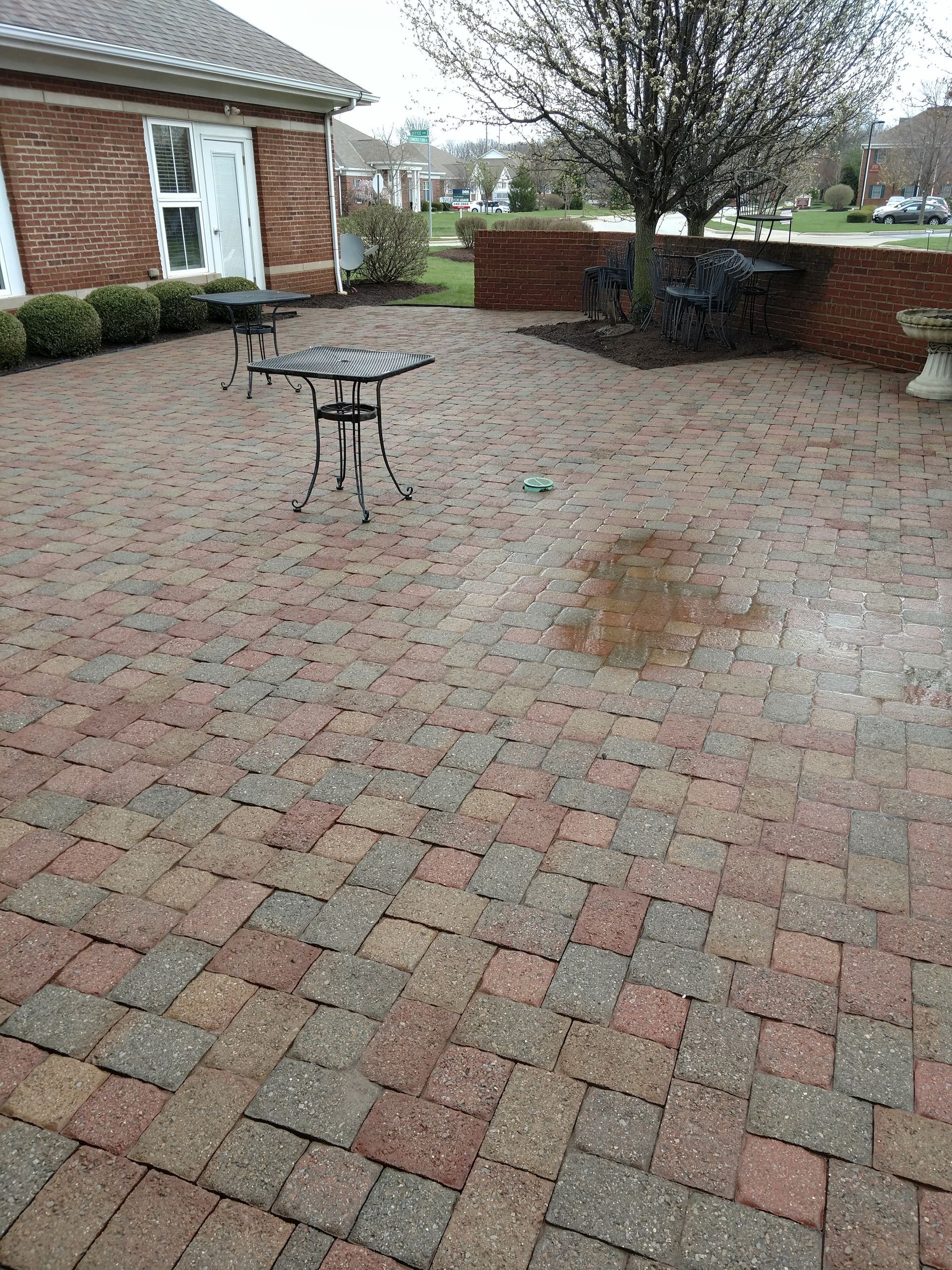 A brick patio with a table and chairs in front of a brick house.