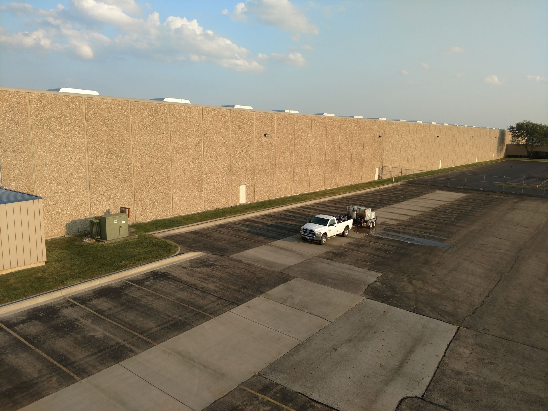 Two white trucks are parked in front of a large building.
