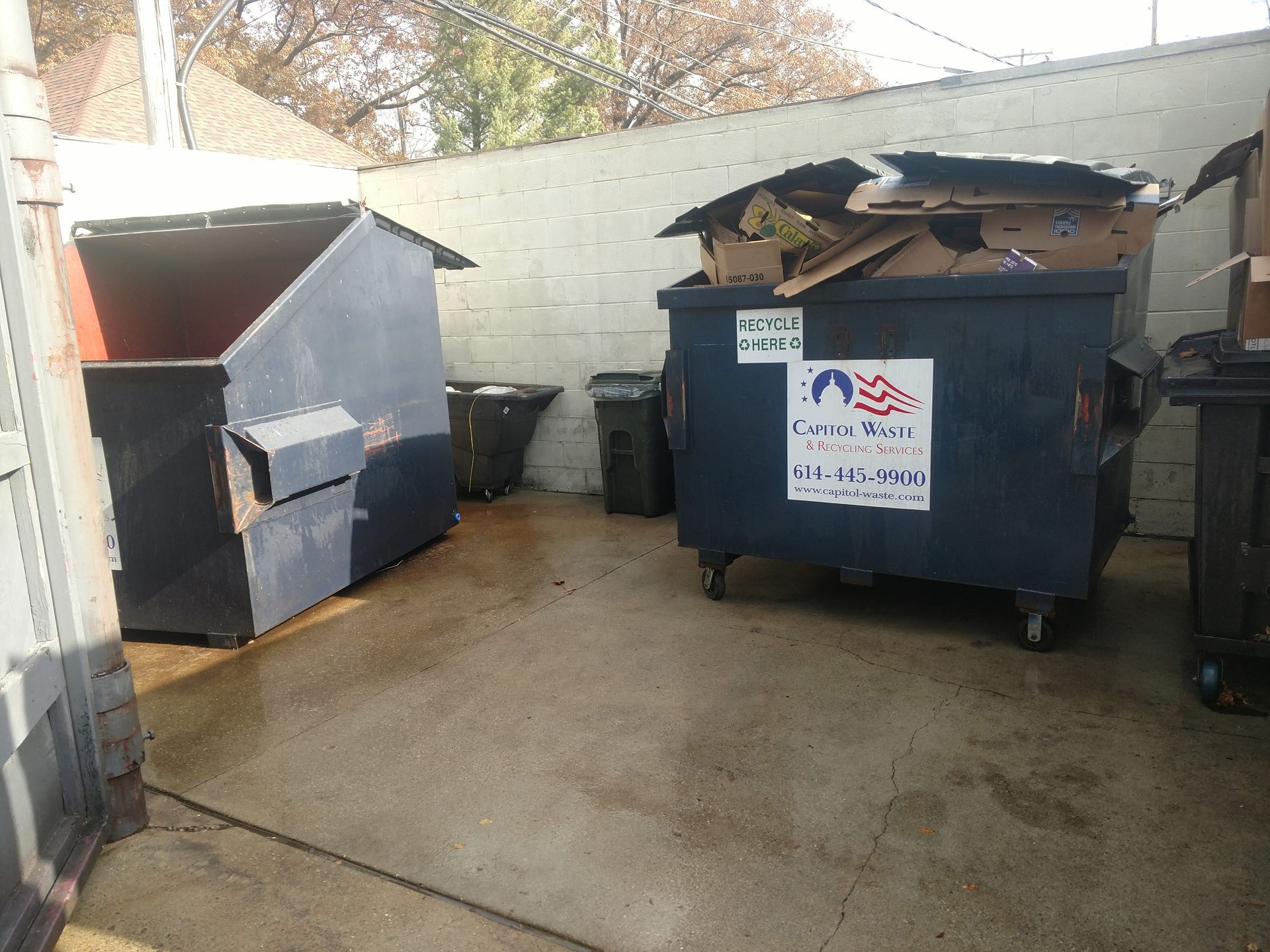 A dumpster with an american flag on it is filled with cardboard boxes.