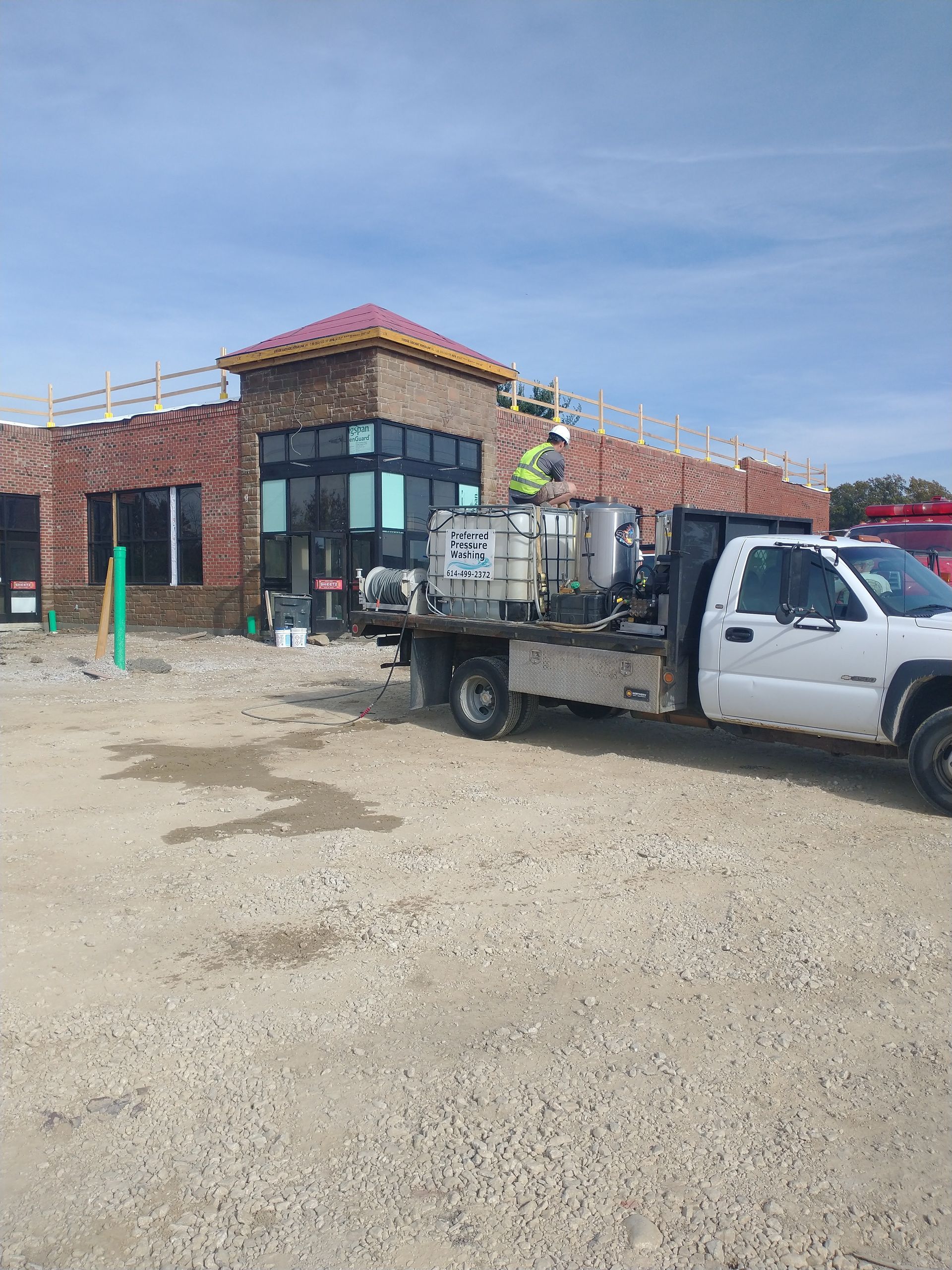 A white truck is parked in front of a building under construction.