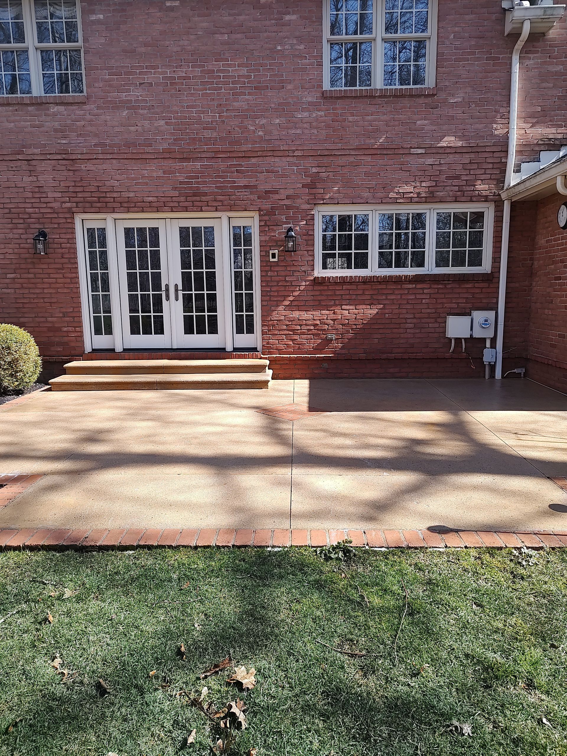 The back of a brick house with a patio and sliding glass doors.