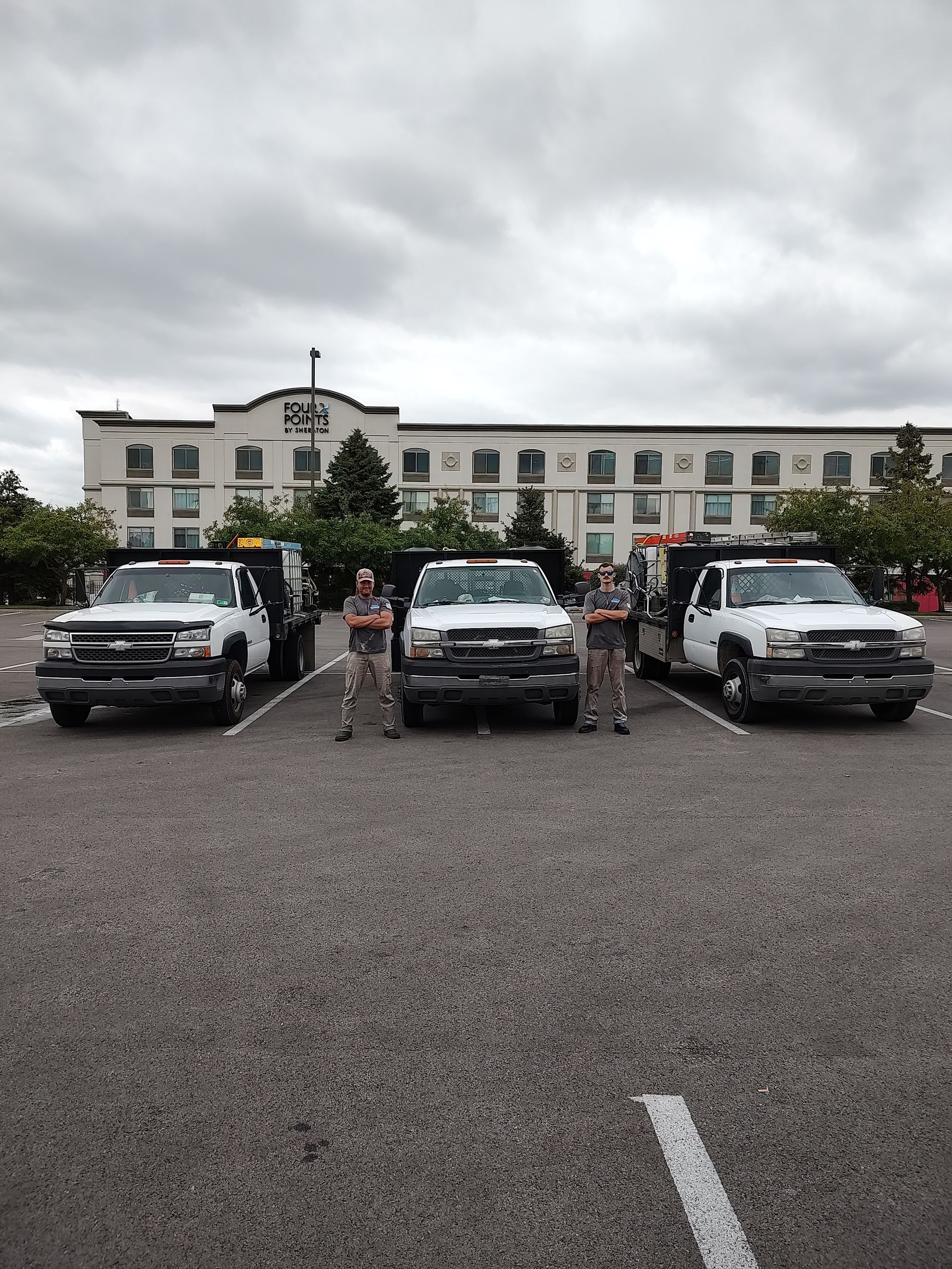 Three trucks are parked in a parking lot in front of a building.
