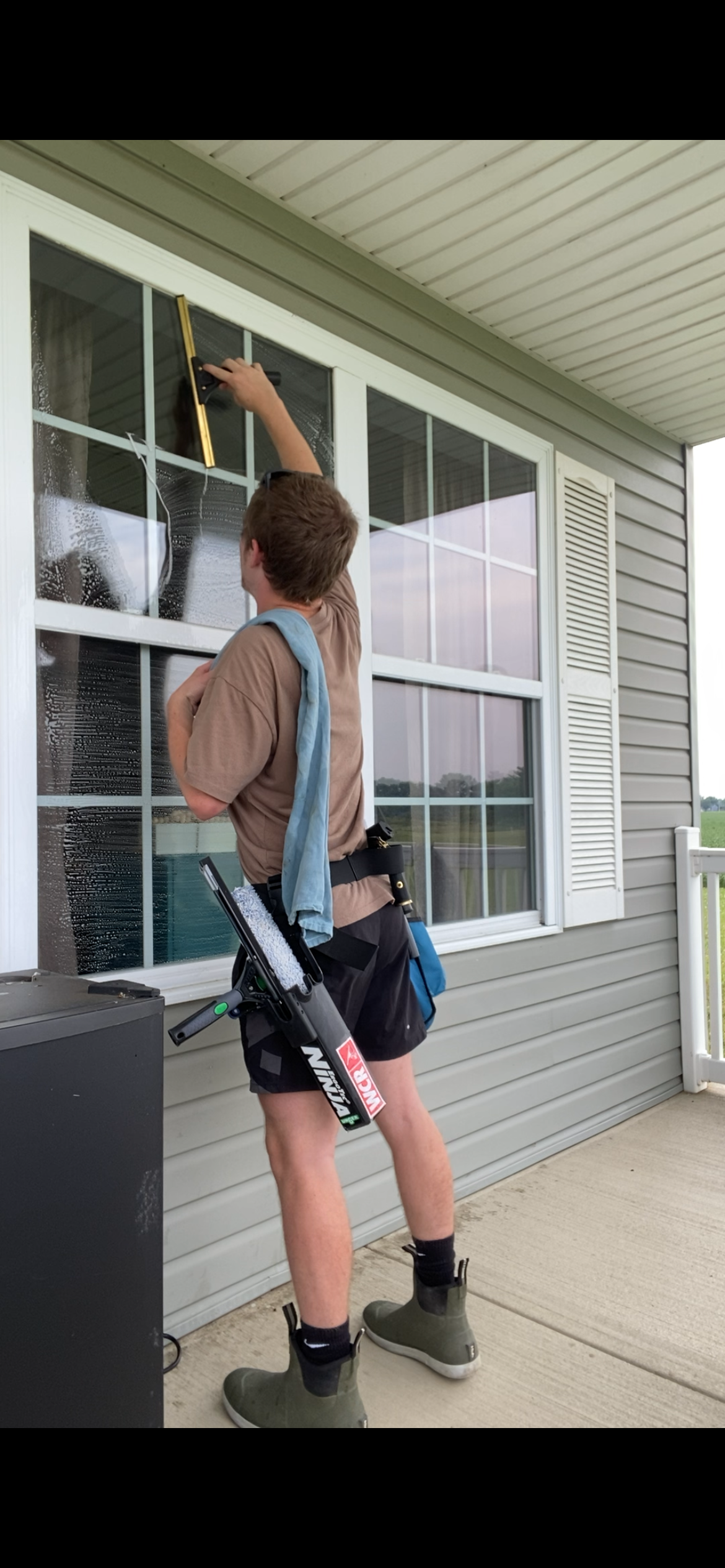 A man is cleaning a window on the side of a house.