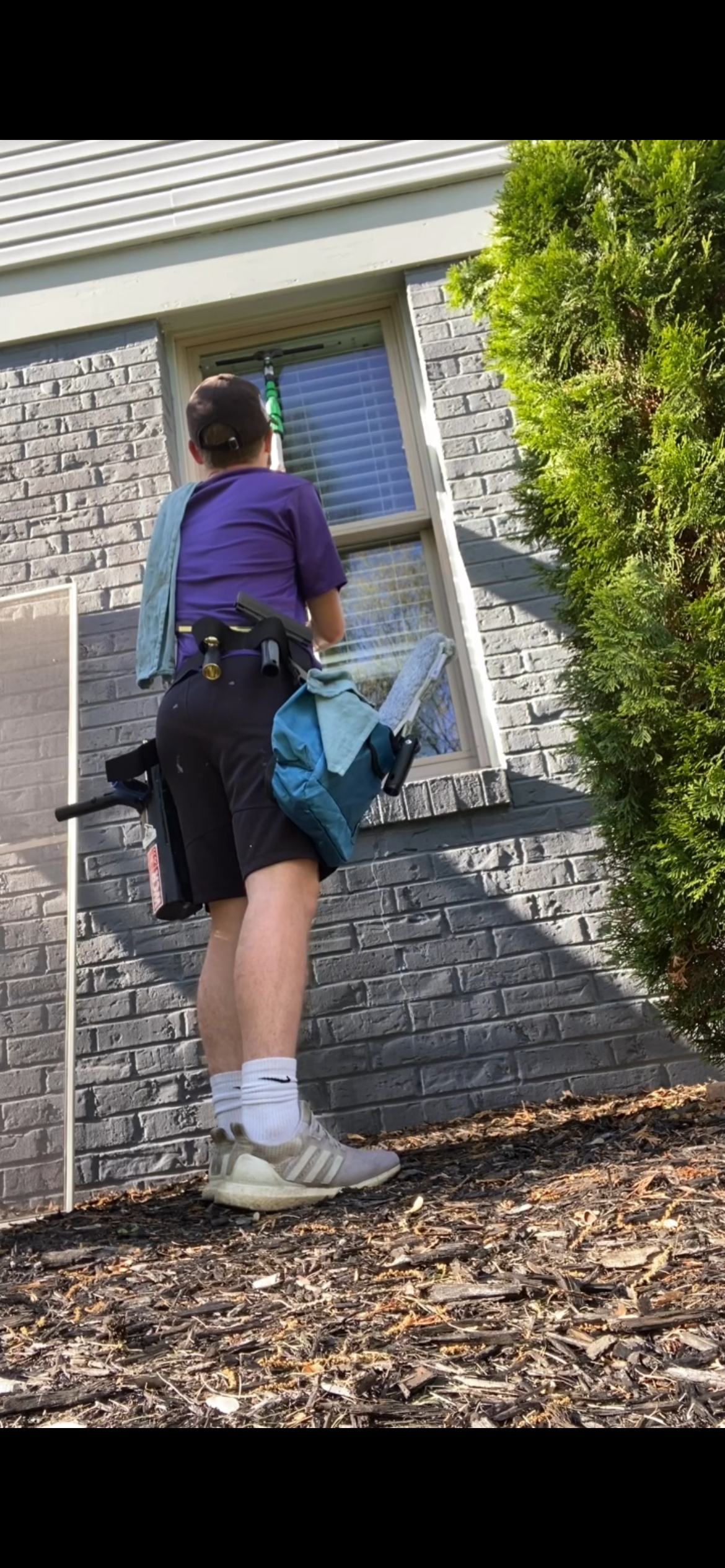 A woman is cleaning a window on the side of a building.