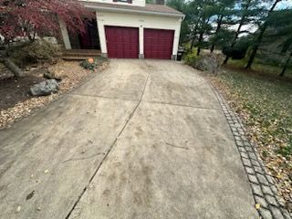 A concrete driveway leading to a house with red garage doors .