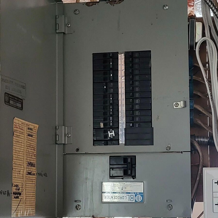 An open electrical breaker panel with a main disconnect at the bottom and multiple circuit breakers in two columns.