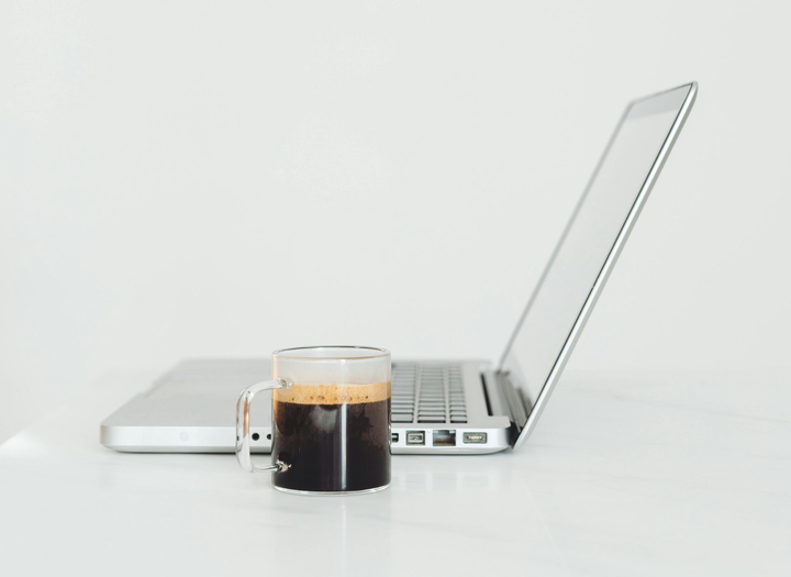 Coffee mug beside an open silver laptop on a white desk