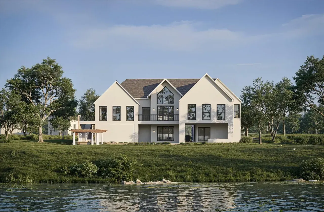 Modern white house with stone accents, two-car garage, and a curved driveway in a sunny setting.