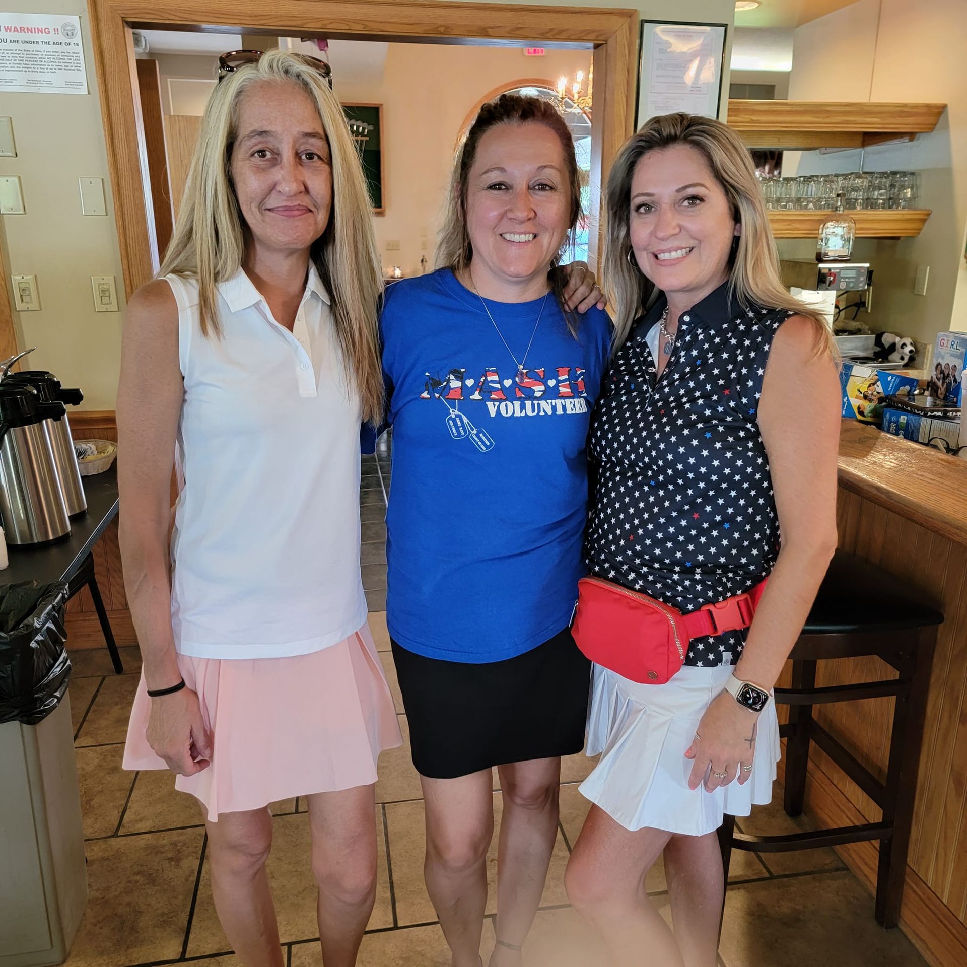Three women are posing for a picture with one wearing a shirt that says palestine