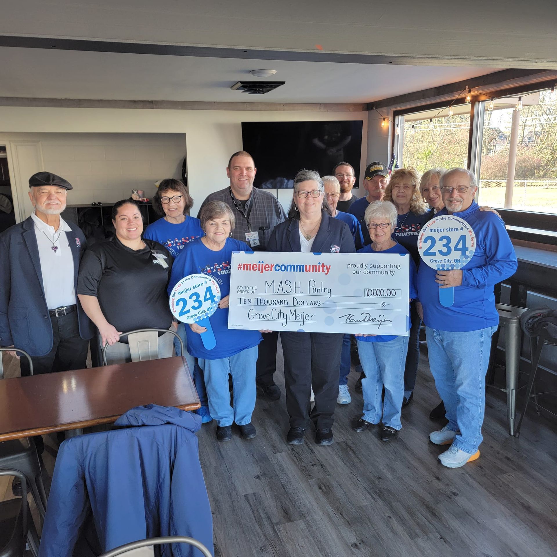 A group of people are posing for a picture while holding a large check.