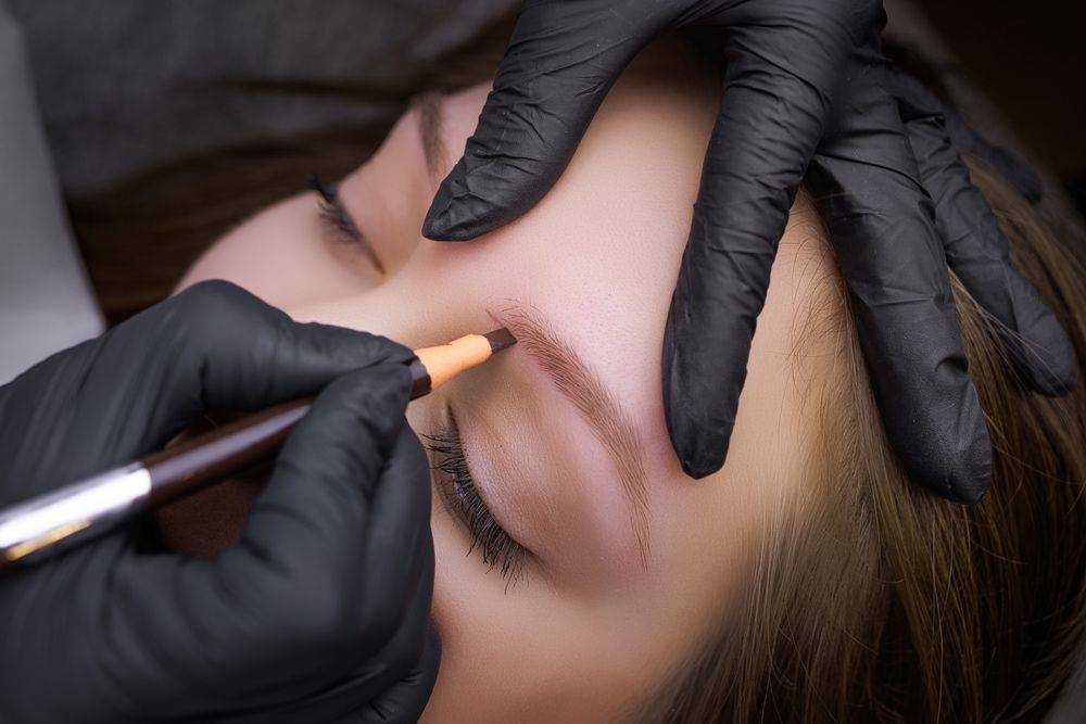 Person getting their eyebrow tattooed by someone wearing black gloves. — Wow! Excellence in Hair in Toowoomba, QLD