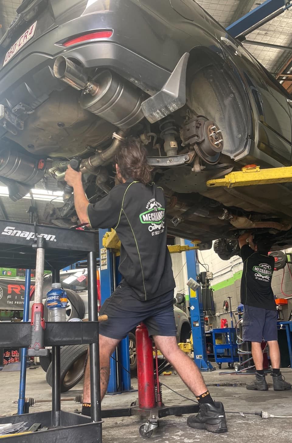 Mechanic Working Under A Lifted Car In An Auto Repair Shop — Mr Mechanical Auto Service Centre in Southport, QLD