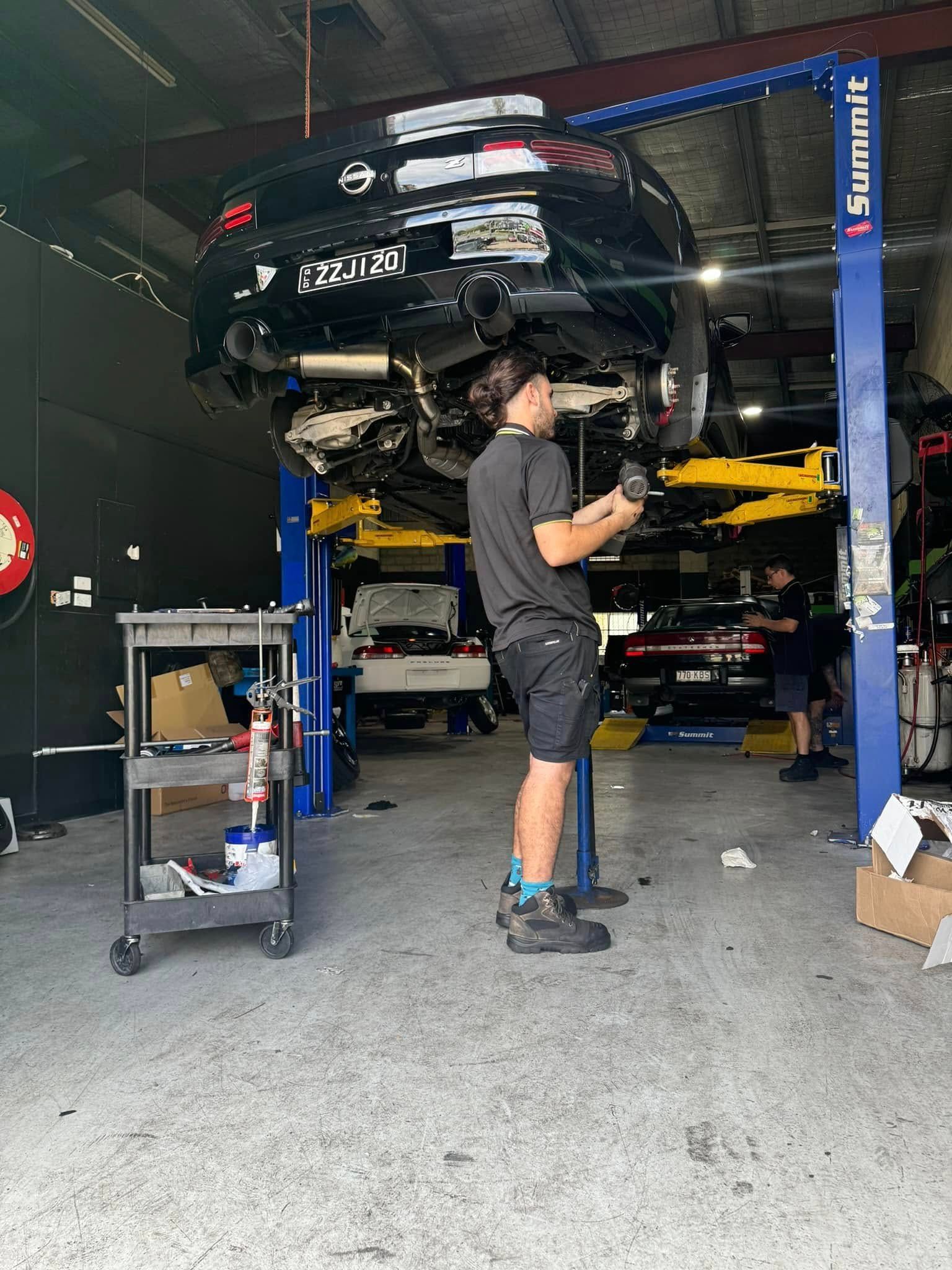 Mechanic Working Under A Raised Black Car — Mr Mechanical Auto Service Centre in Southport, QLD