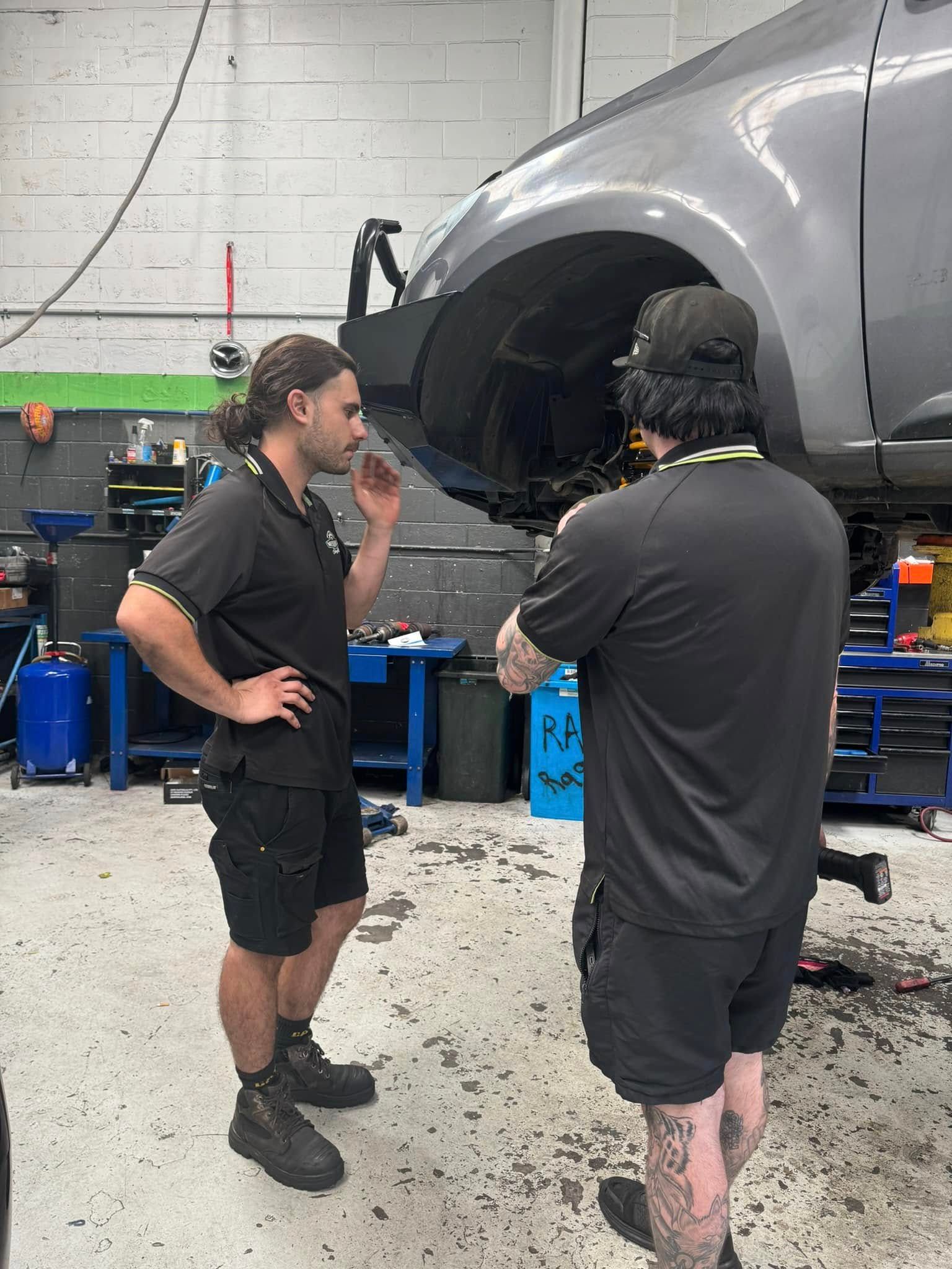 Two Mechanics Discussing A Raised Silver Car In An Auto Repair Shop — Mr Mechanical Auto Service Centre in Southport, QLD