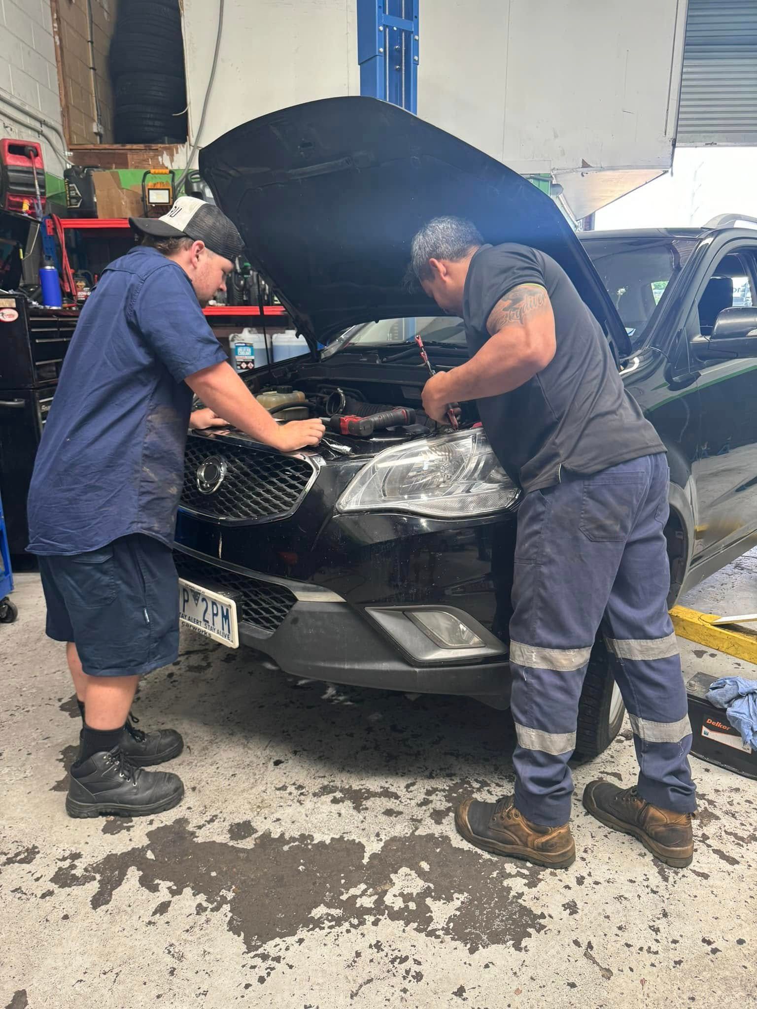Two Mechanics Working Under A Raised Hood On A Black Car — Mr Mechanical Auto Service Centre in Southport, QLD