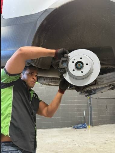Mechanic In Green Shirt Working On A Car’s Brake Assembly — Mr Mechanical Auto Service Centre in Southport, QLD