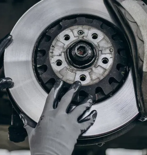 Gloved Hands Inspecting A Car Brake Rotor And Hub Assembly — Mr Mechanical Auto Service Centre in Southport, QLD