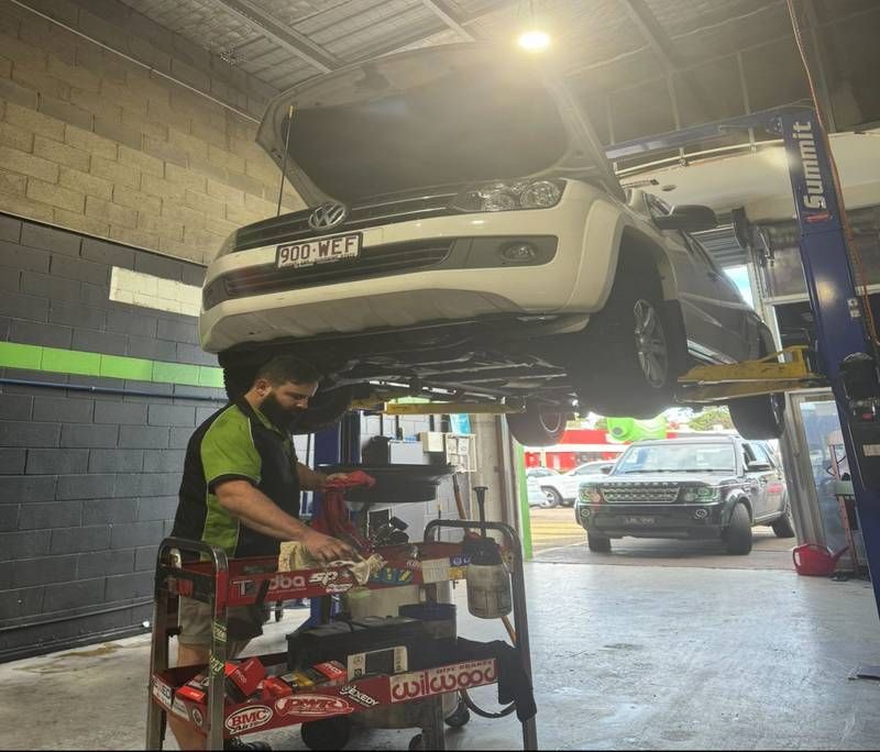 Mechanic Working Under A Raised White SUV — Mr Mechanical Auto Service Centre in Southport, QLD