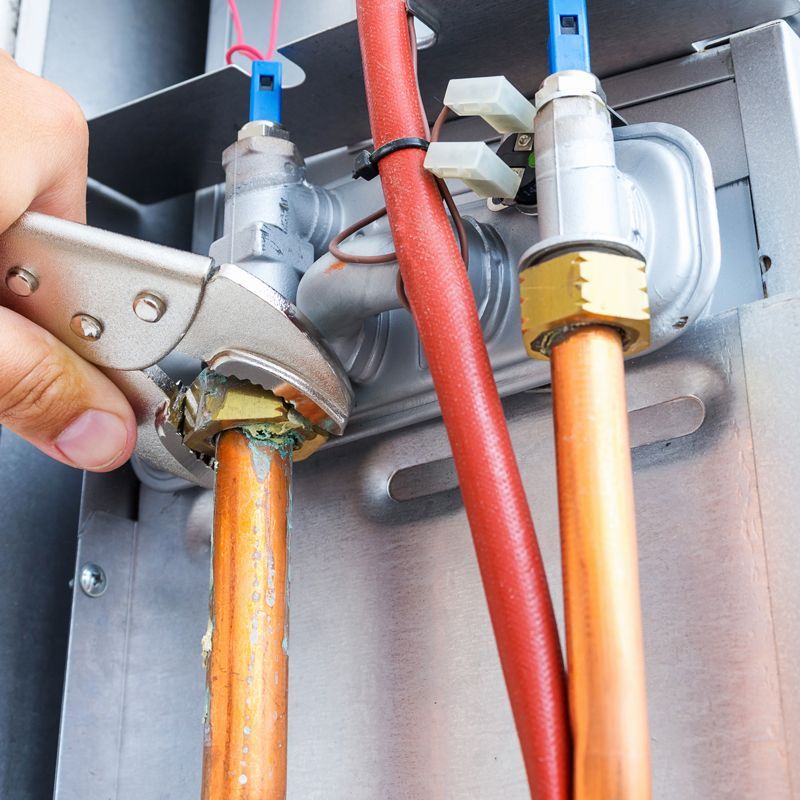 Hand connecting orange and red electrical cables to a metal panel with wire connectors