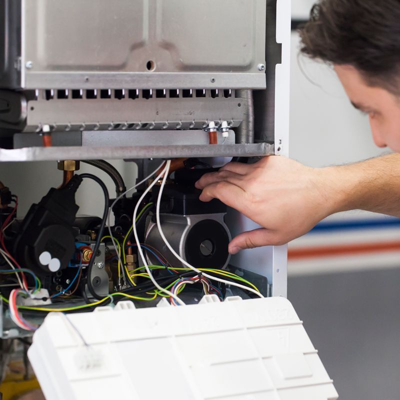 Technician repairing electrical wiring inside an open appliance panel